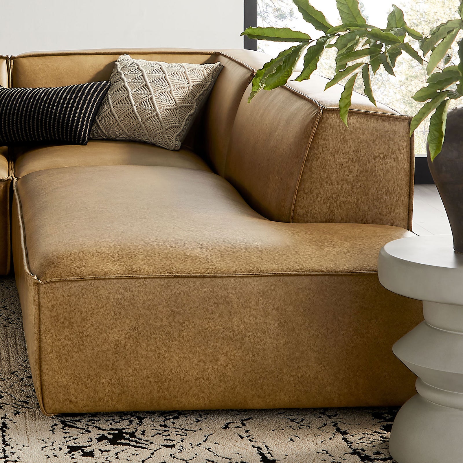 Curved corner of the toast sectional styled with textured accent pillows for inviting comfort. || EEI-7414-TST || detail_room