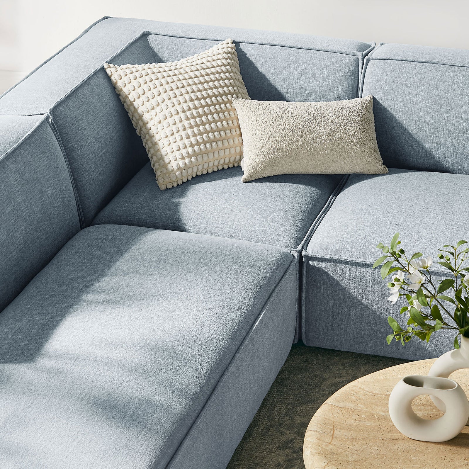 Textured accent pillows and soft performance fabric create a cozy corner on the sky blue modular sectional || EEI-7415-SKY || detail_room