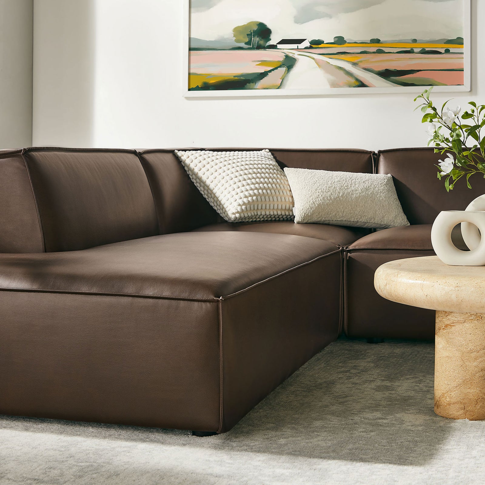 Espresso sectional seating anchors a modern living area with cozy pillows, artwork, and a sculptural table || EEI-7416-ESP || detail_room