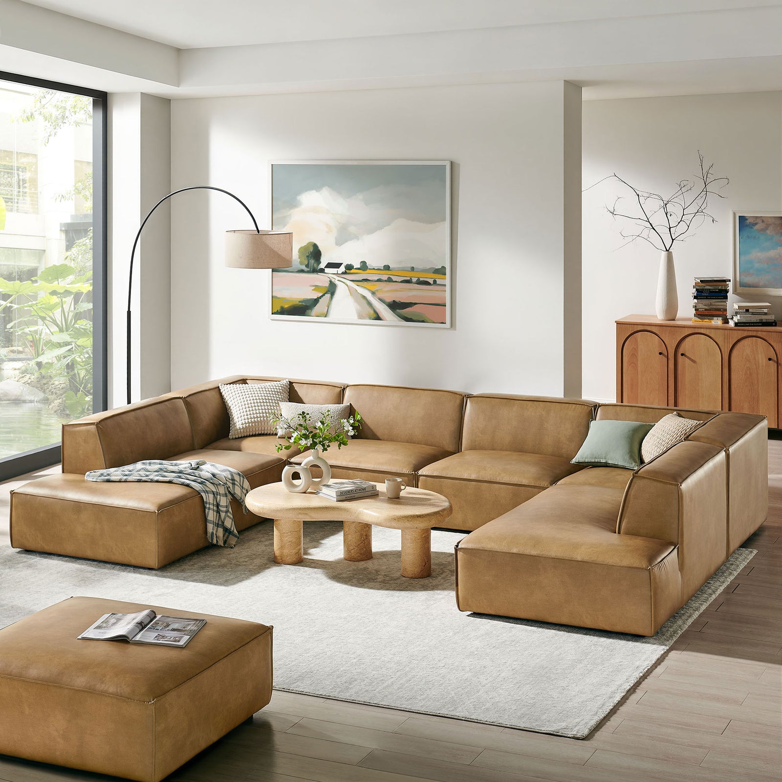 Toast vegan leather U-shaped sectional styled in a bright living room with round coffee table || EEI-7416-TST || front_angle_room