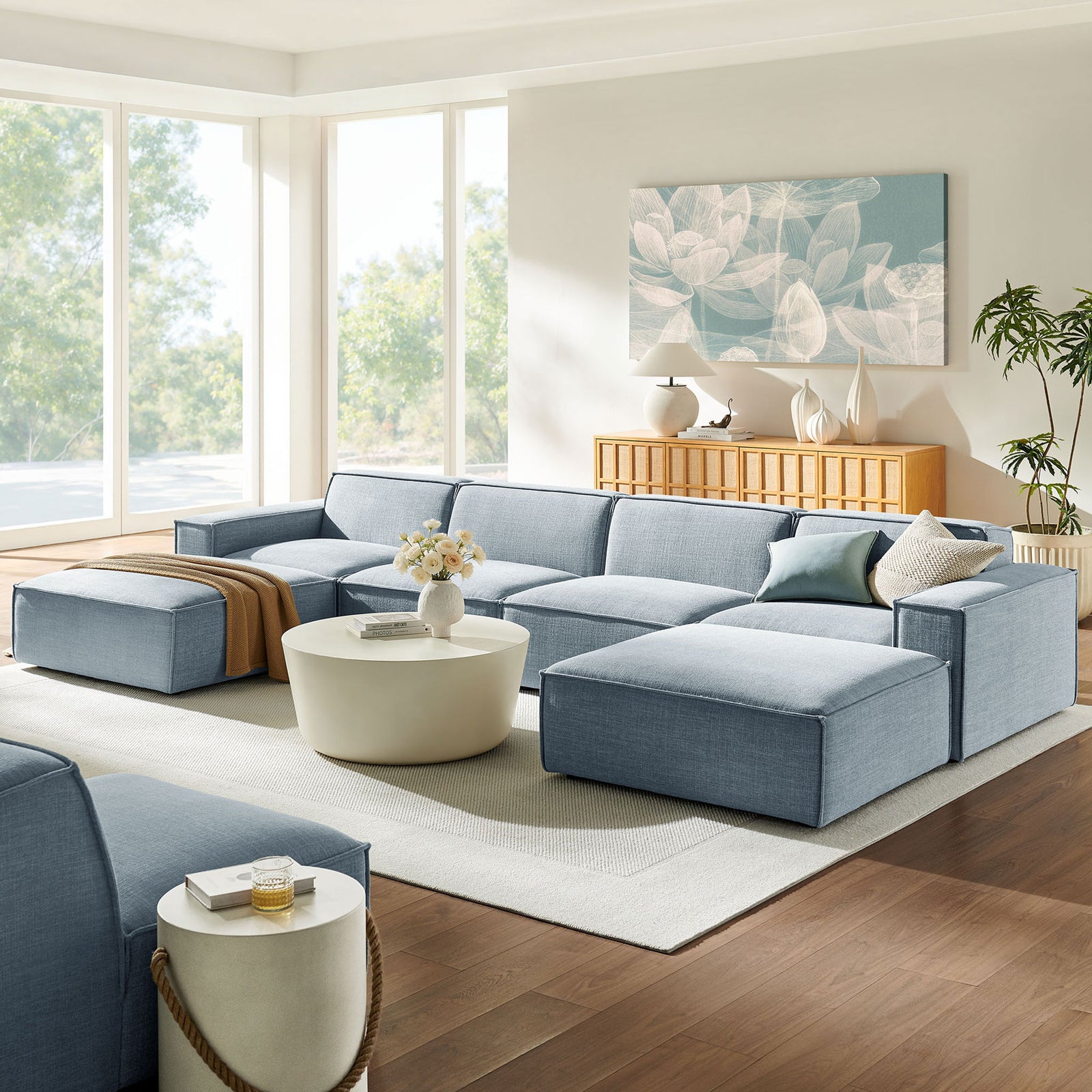 Sky blue modular sectional styled with throw blanket, flowers, and modern artwork in a sunny room || EEI-7417-SKY || front_room