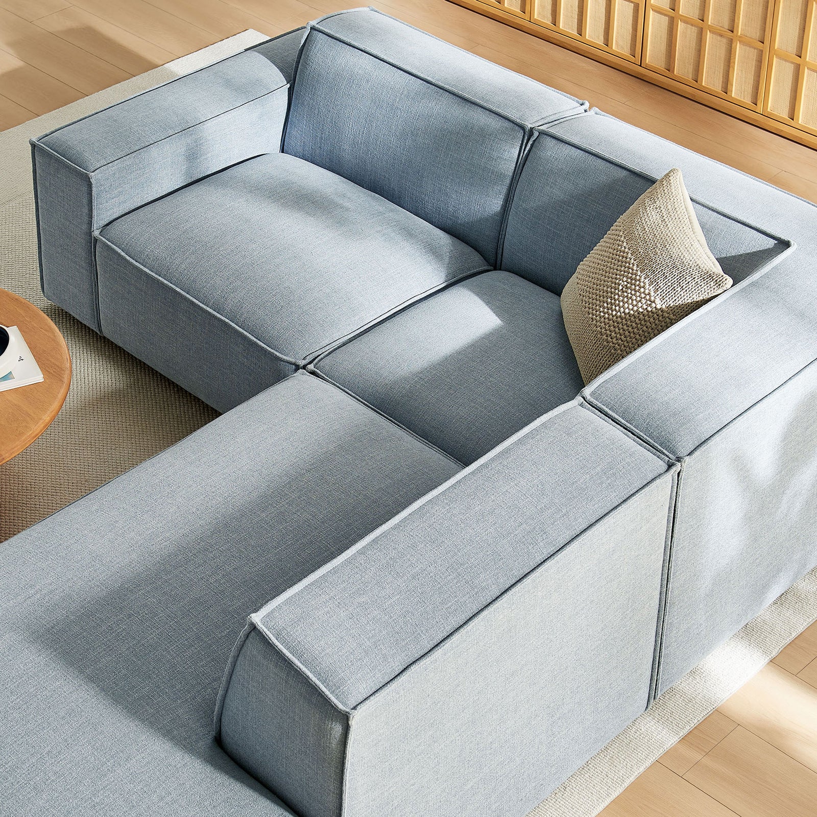 Spacious L-shaped sectional in sky blue performance fabric styled with warm wood tables and soft neutral rug || EEI-7421-SKY || top_angle_room
