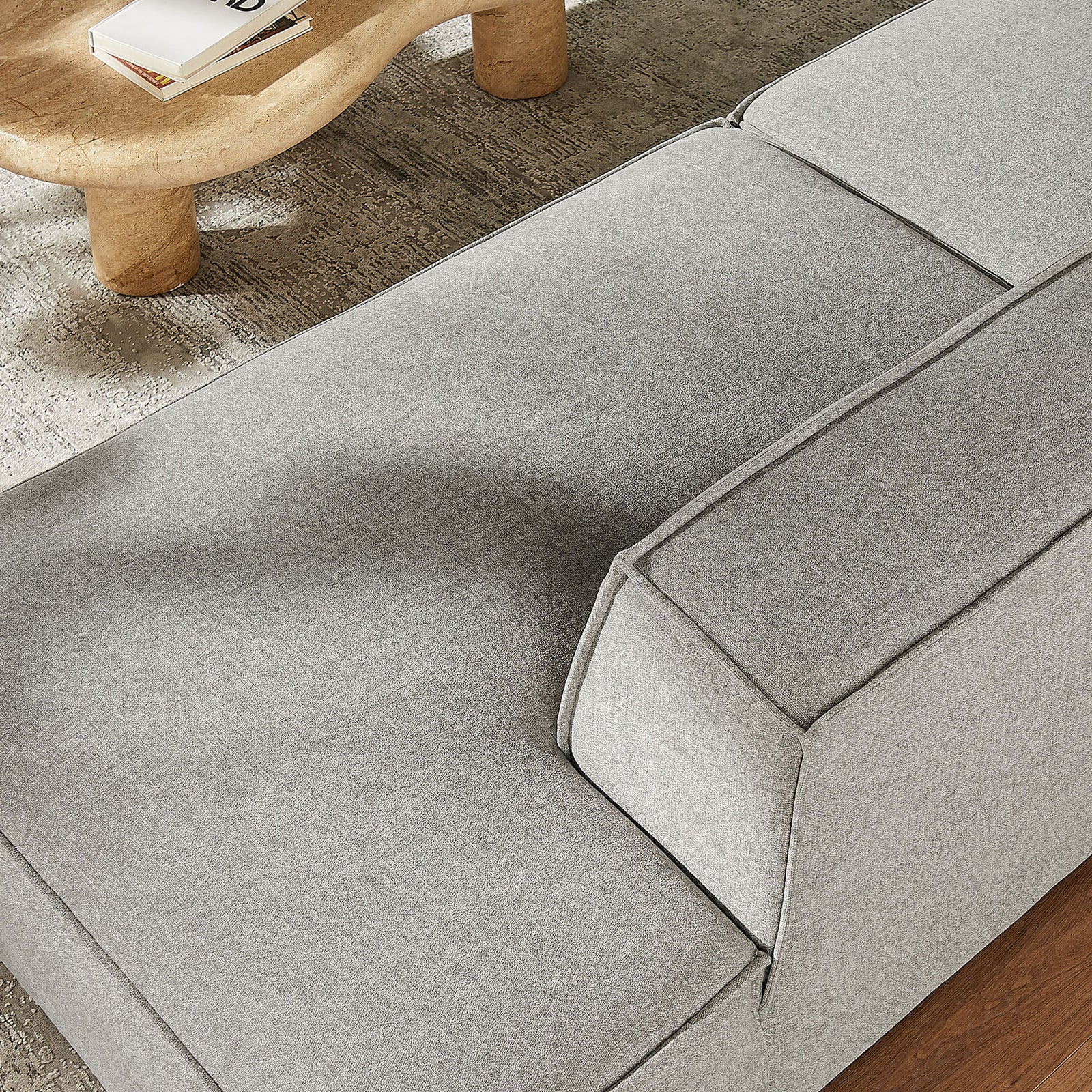 Detail of chaise seat showing smooth performance upholstery and plush cushioning beside a wood table. || EEI-7425-PEW || detail_room