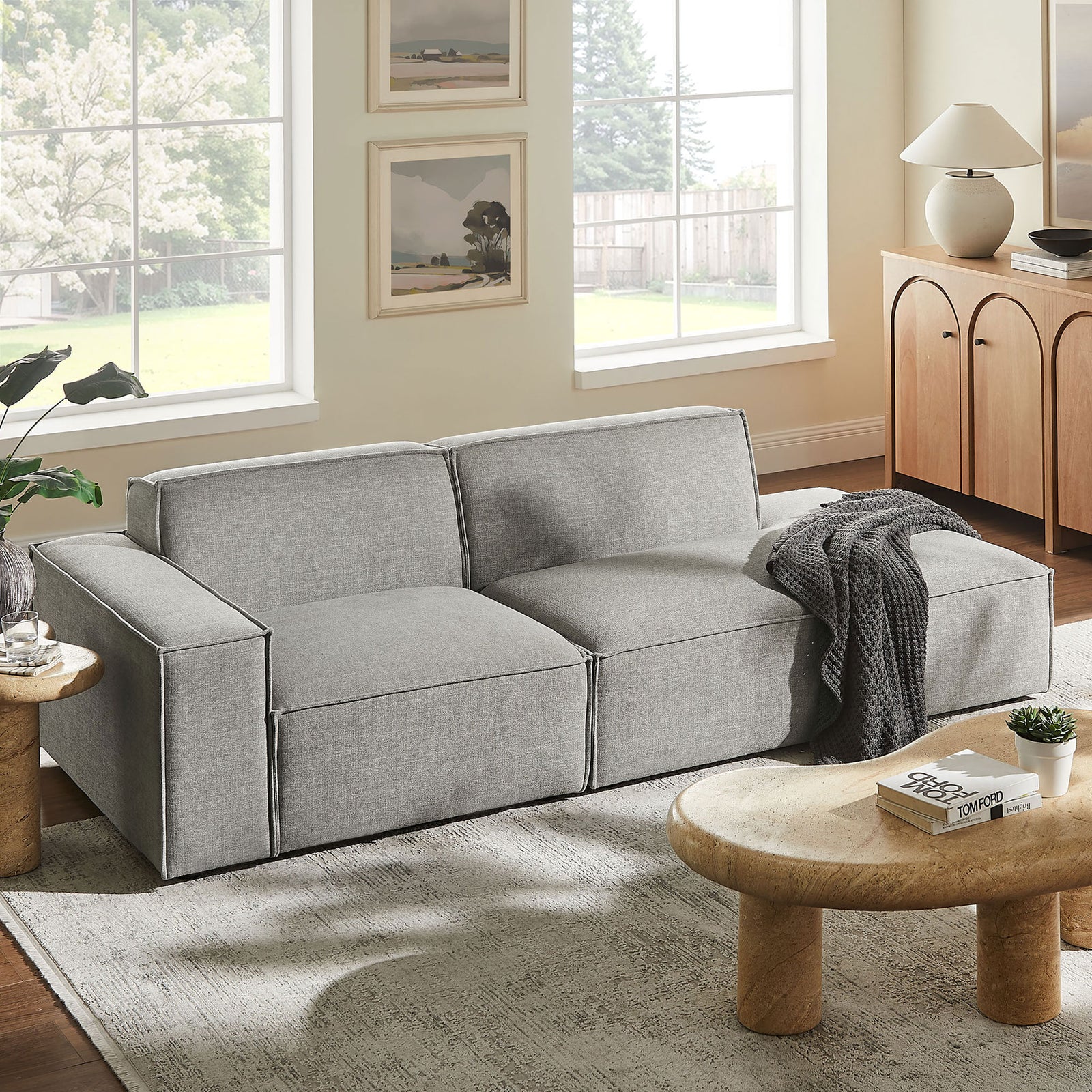 Pewter modular loveseat styled in a bright living room with cozy rug and sculpted wood coffee table. || EEI-7425-PEW || front_angle_room
