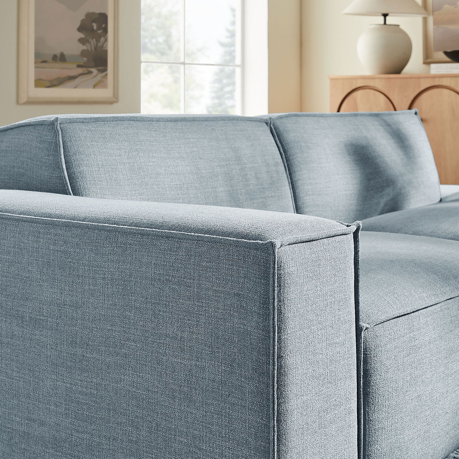 Clean lined left armrest and back cushions in sky blue weave add modern texture to the living room scene || EEI-7425-SKY || detail_room