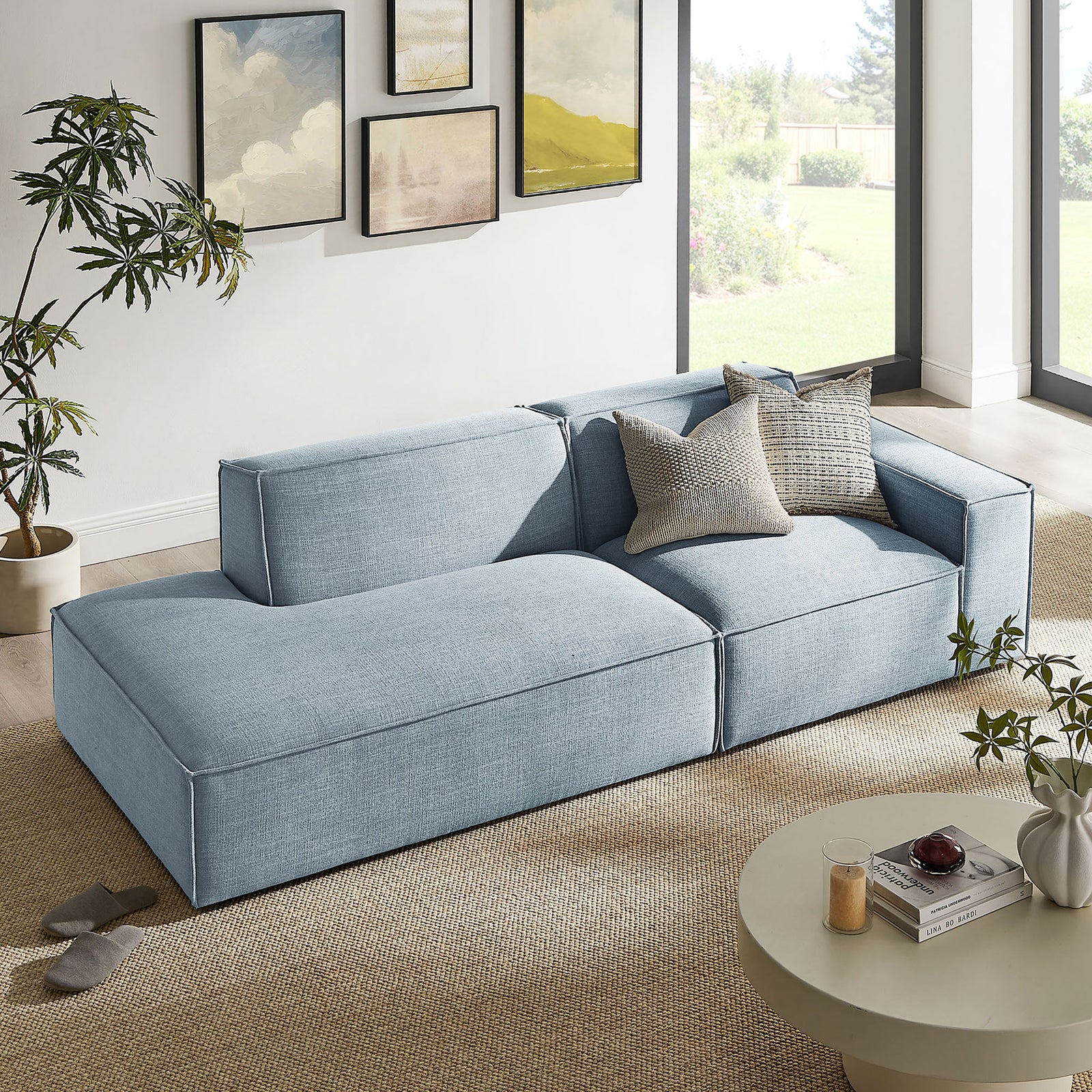Sky blue modular loveseat softens a sunny living room with generous chaise, accent pillows, and tailored lines || EEI-7427-SKY || front_angle_room