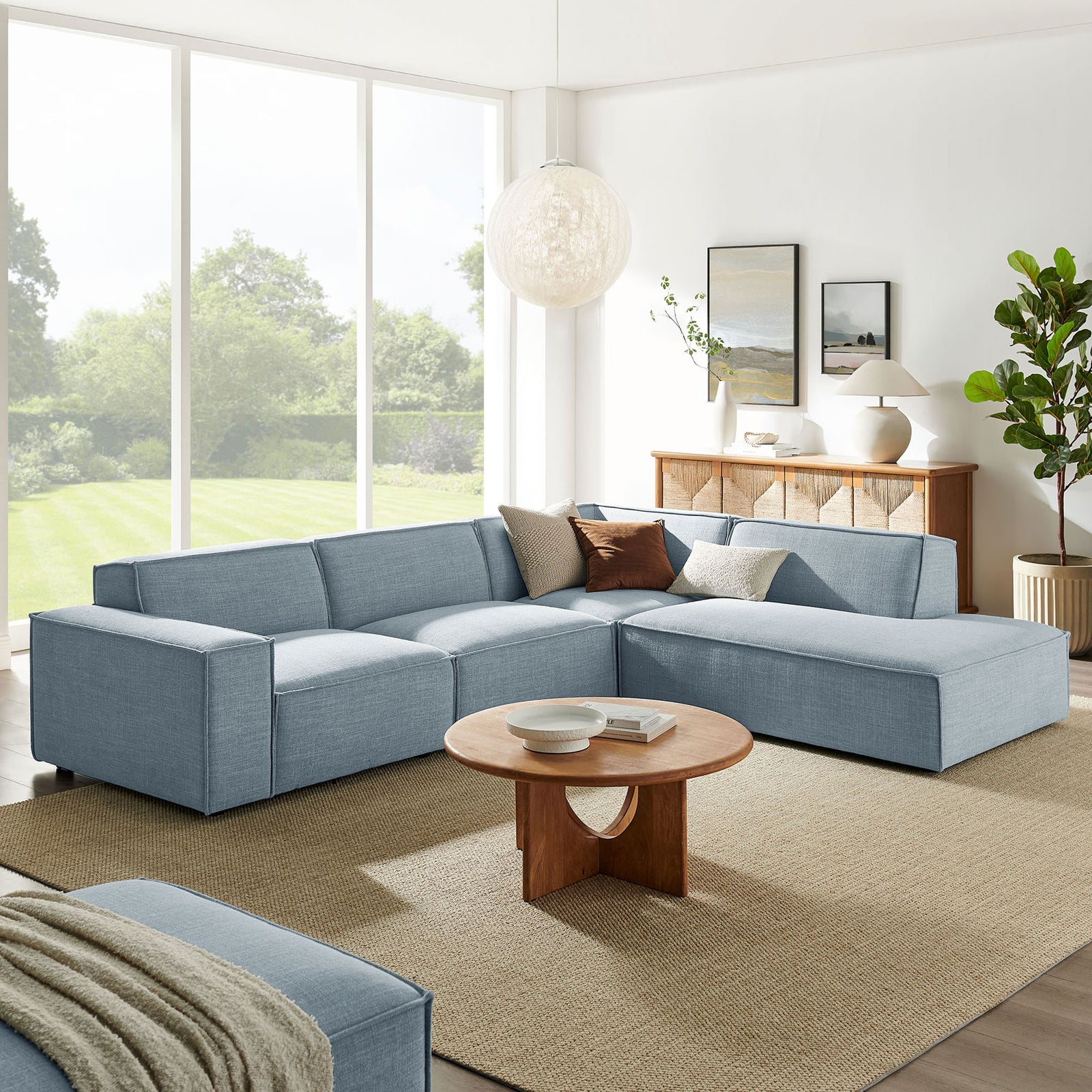 Sky blue modular sectional with right-facing chaise styled in a bright living room with round wood table || EEI-7429-SKY || front_angle_room