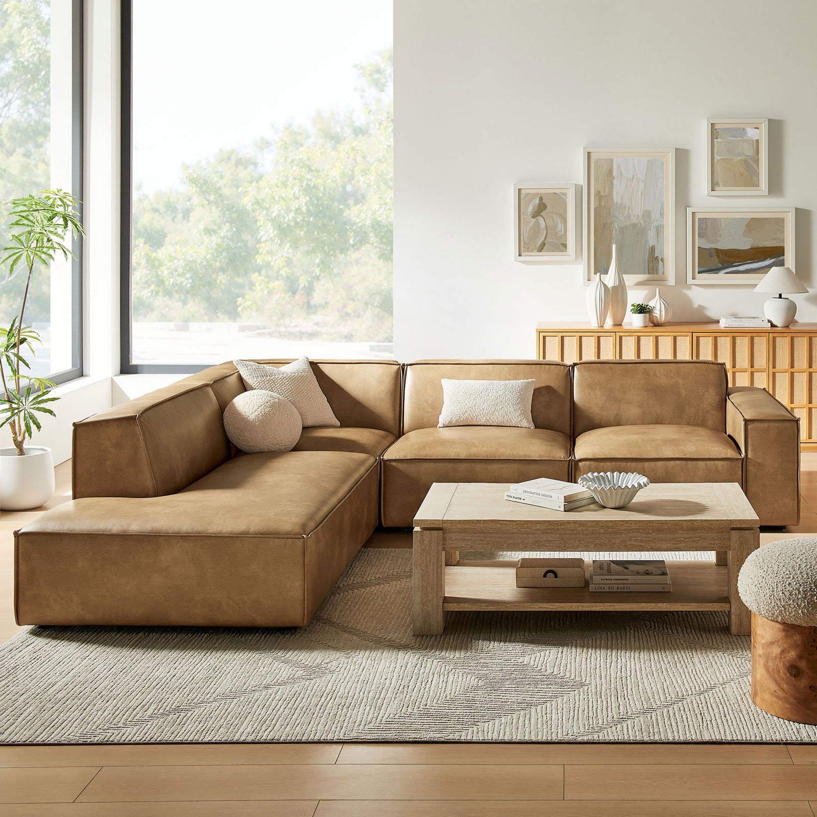 Toast vegan leather sectional styled with neutral pillows in a bright living room with wood coffee table || EEI-7432-TST || front_room