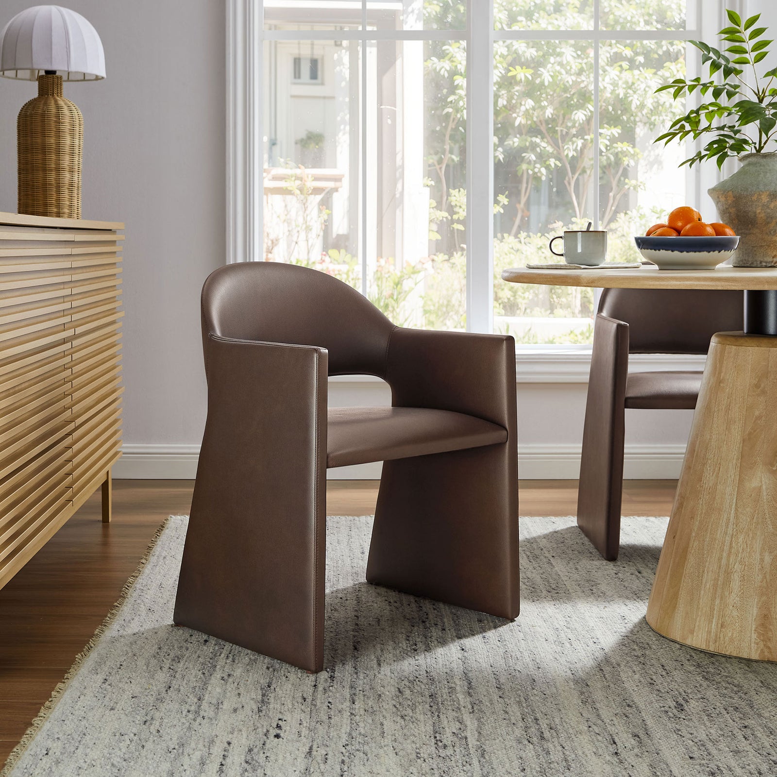 Espresso vegan leather dining armchair styled in a sunlit dining room with round table and warm natural decor || EEI-7442-ESP || front_angle_room