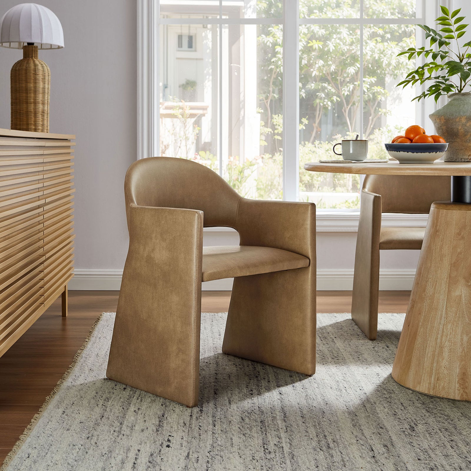 Toast vegan leather dining armchair styled in a bright dining room with wood table and neutral rug || EEI-7442-TST || front_angle_room