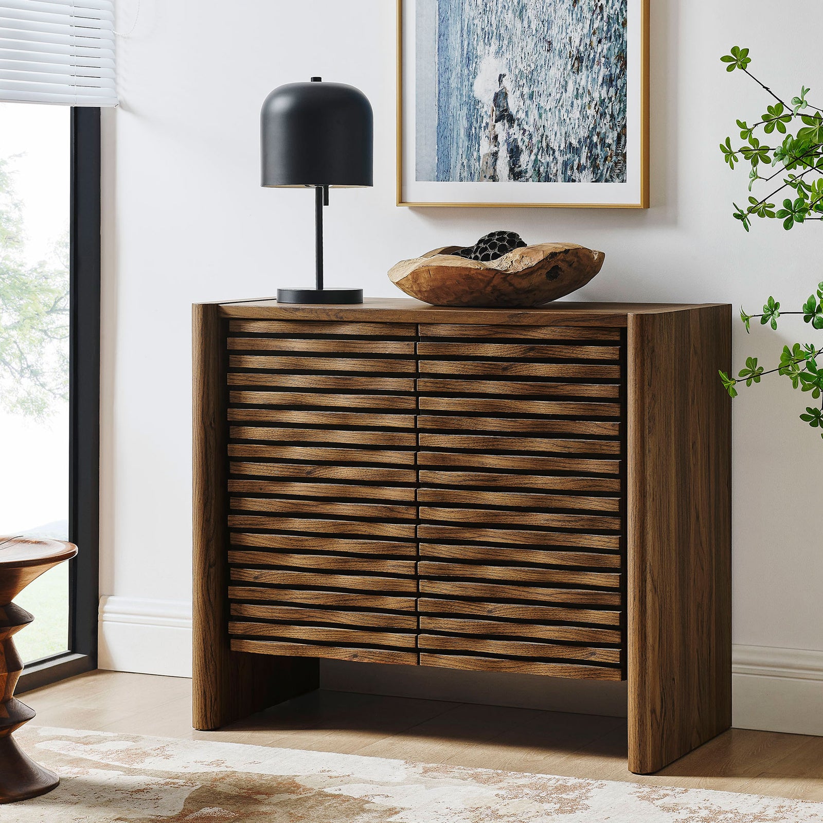 Emric wave cabinet in a modern living room, offering slim storage and display surface. || EEI-7444-WAL || front_angle_room