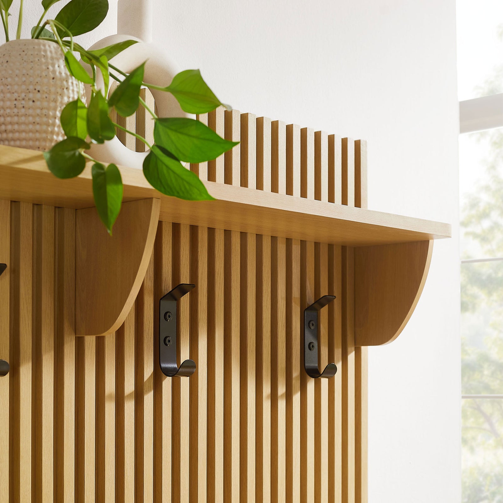 Top display shelf and matte black hooks accent the vertical fluted panel in a warm oak finish || EEI-7473-OAK || detail_room