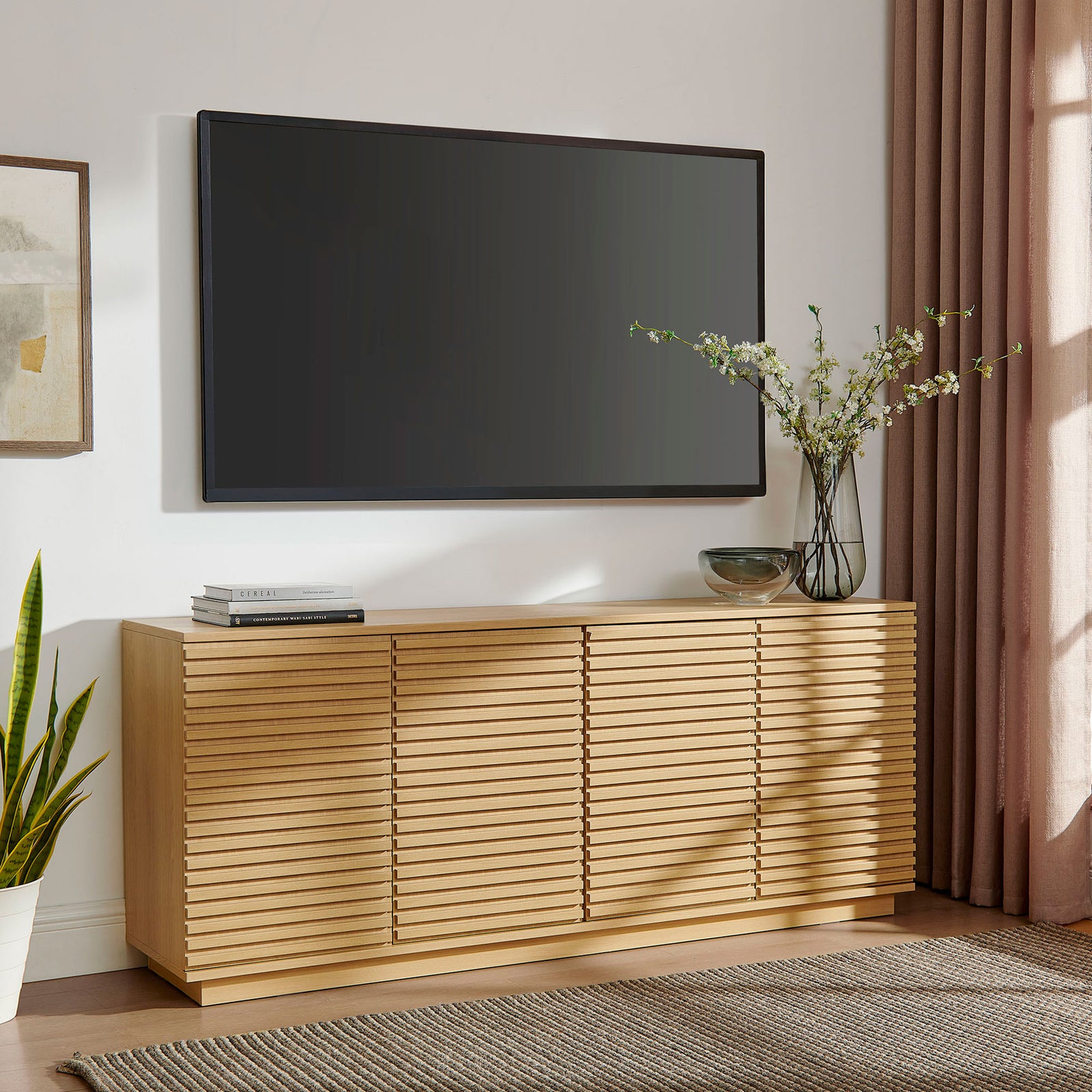 Fluted oak sideboard anchors a media wall beneath a mounted TV with plants and sculptural decor || EEI-7477-OAK || front_angle_room