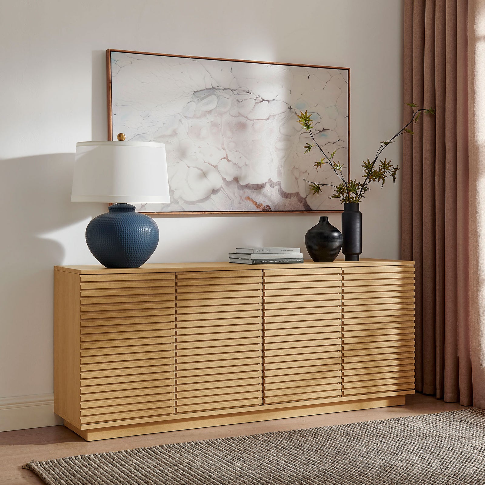 Oak fluted sideboard styled with art, a table lamp, and vases for an inviting, curated living room look || EEI-7477-OAK || front_angle_room