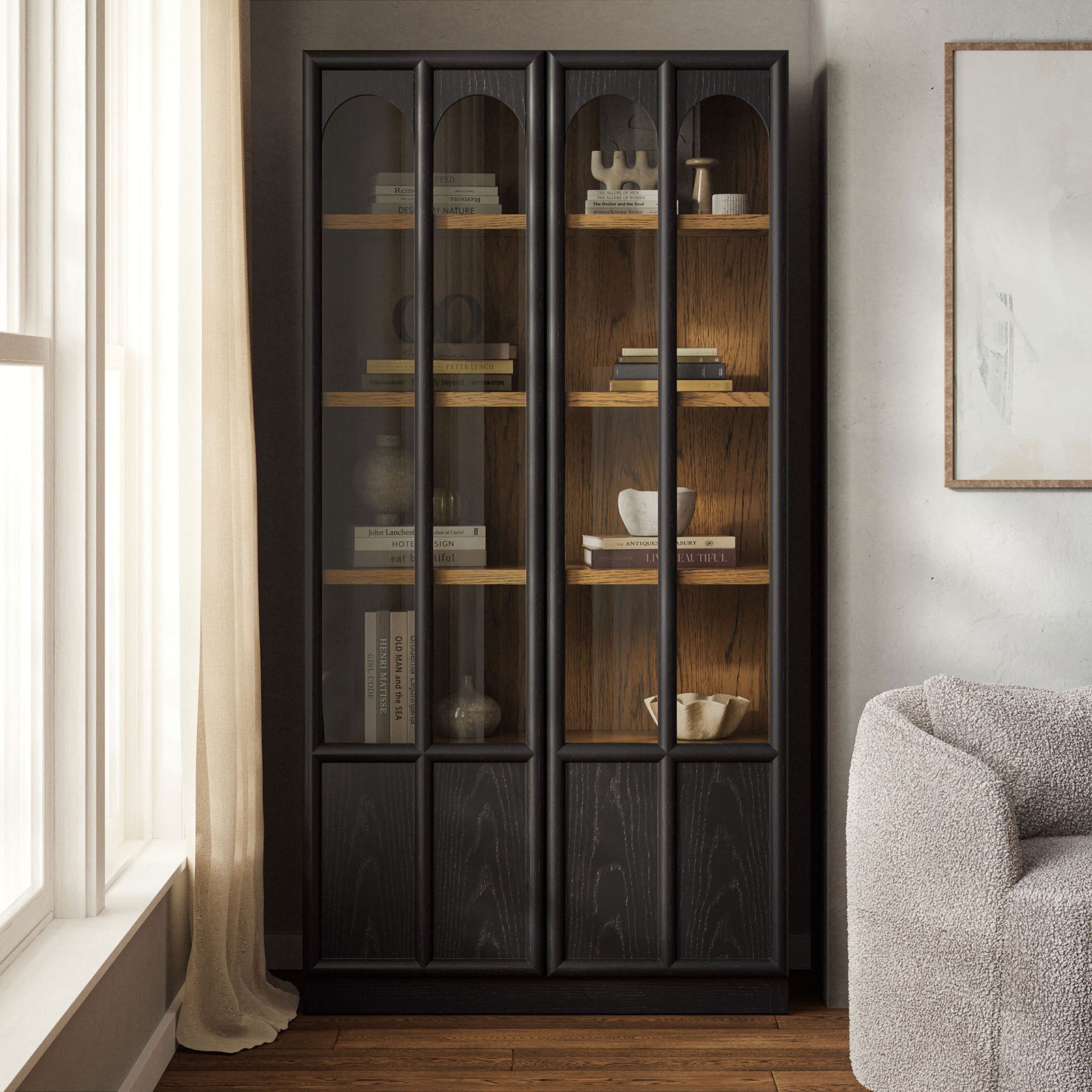 Black oak Anwen display cabinet styled in a bright living room with books and decor behind glass doors || EEI-7484-BLK-OAK || front_angle_room