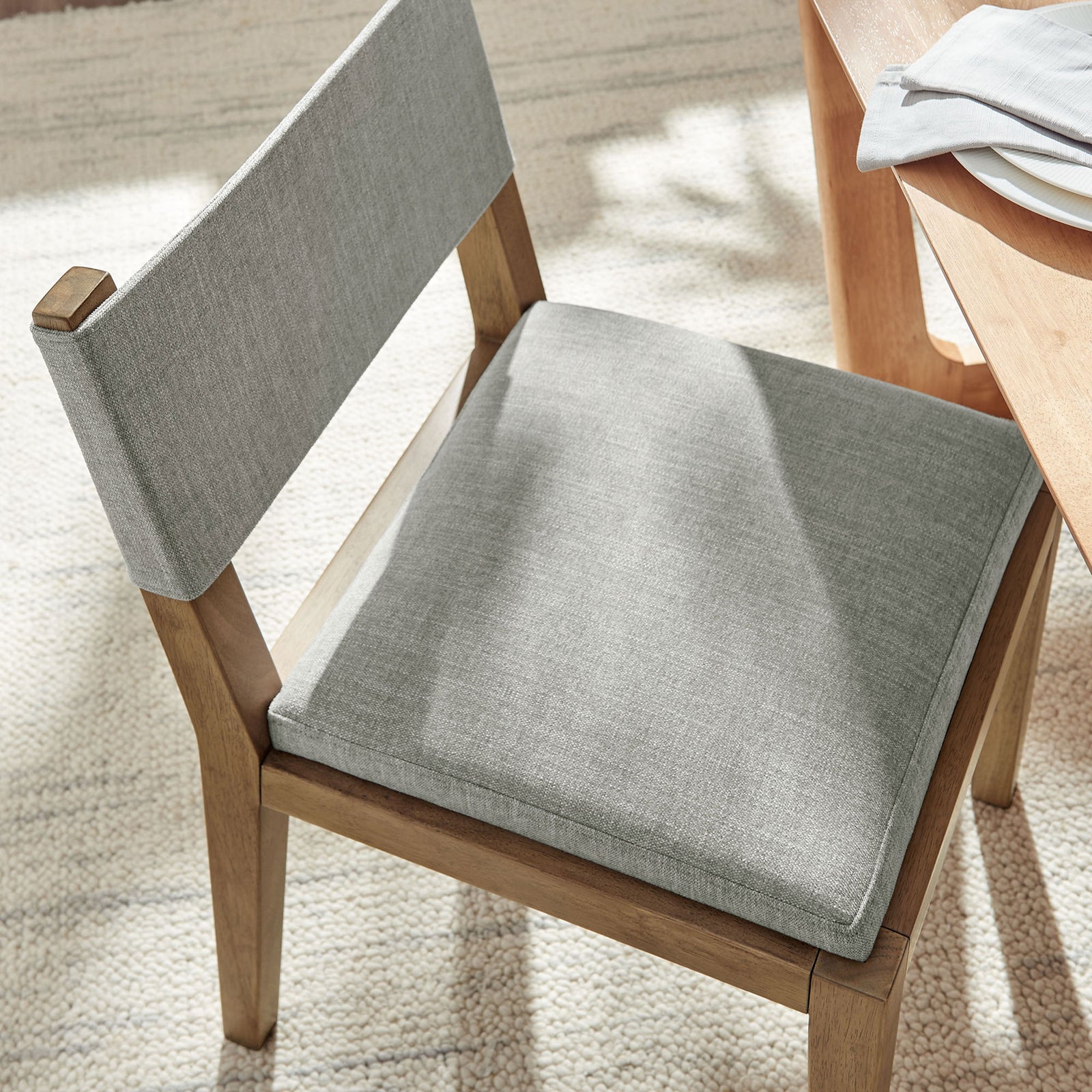 Calder dining chair in wheat fabric styled at a light wood table over a plush neutral rug || EEI-7485-HEW || detail_room