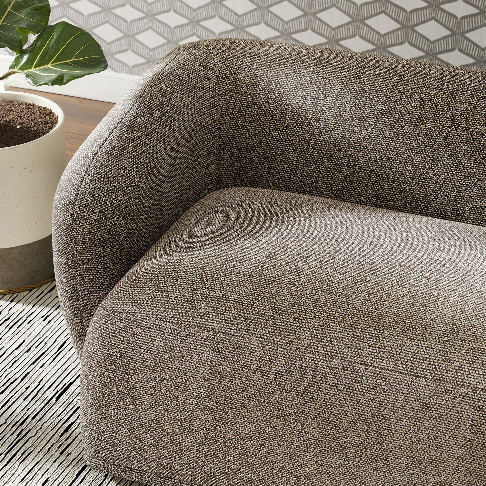 Curved arm of the earth boucle sofa styled with patterned rug, potted plant, and graphic accent wall || EEI-7501-ETH || detail_room