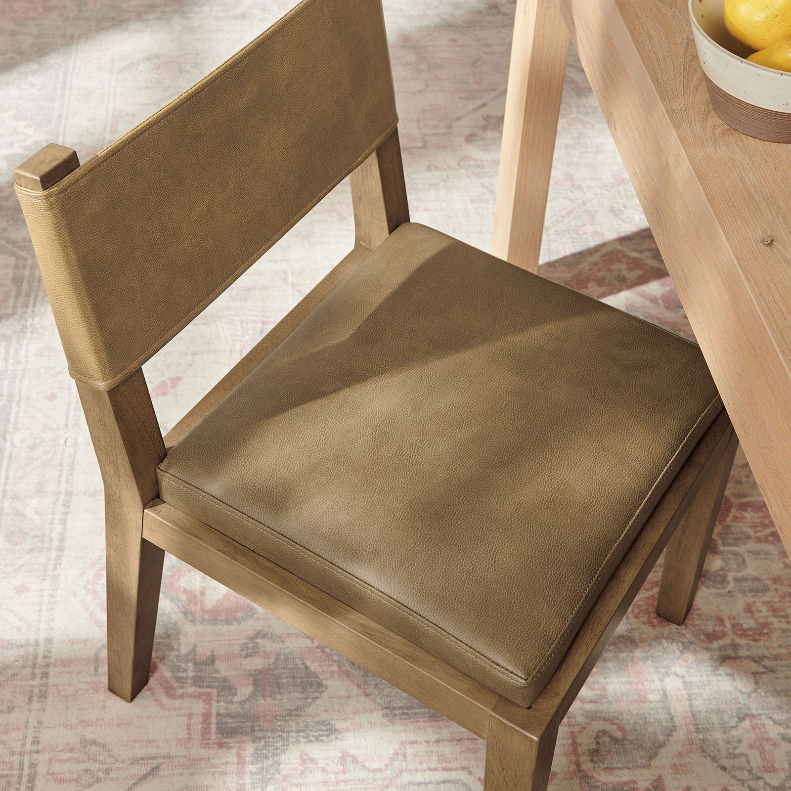 Calder toast vegan leather dining chair at the table, showing the plush seat cushion and smooth, textured upholstery || EEI-7527-TST || detail_room