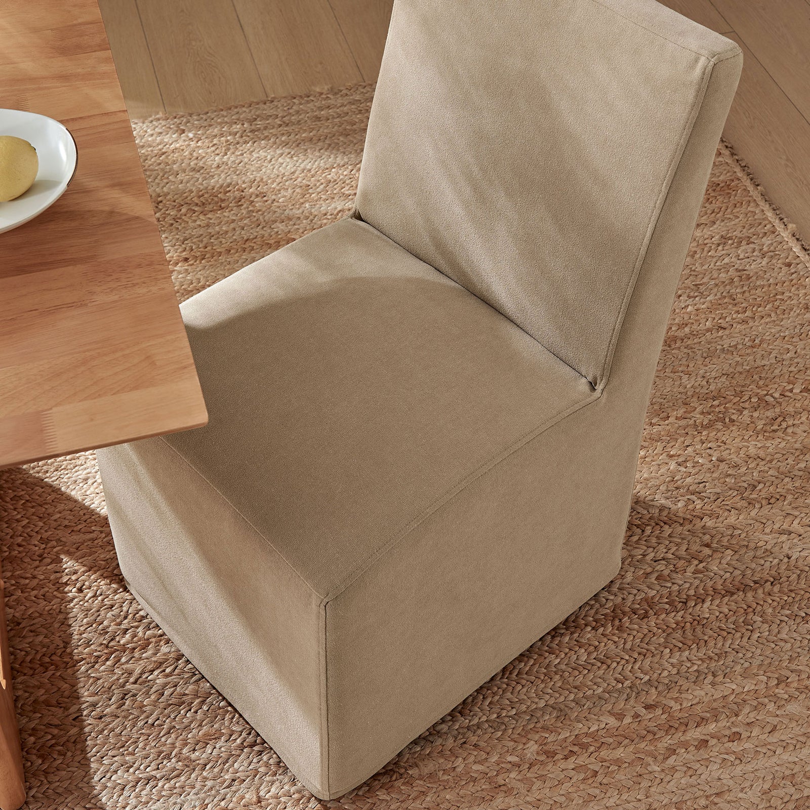 Almond linen-blend slipcovered dining chair tucks neatly at the table on a textured natural rug || EEI-7528-ALM || top_angle_room