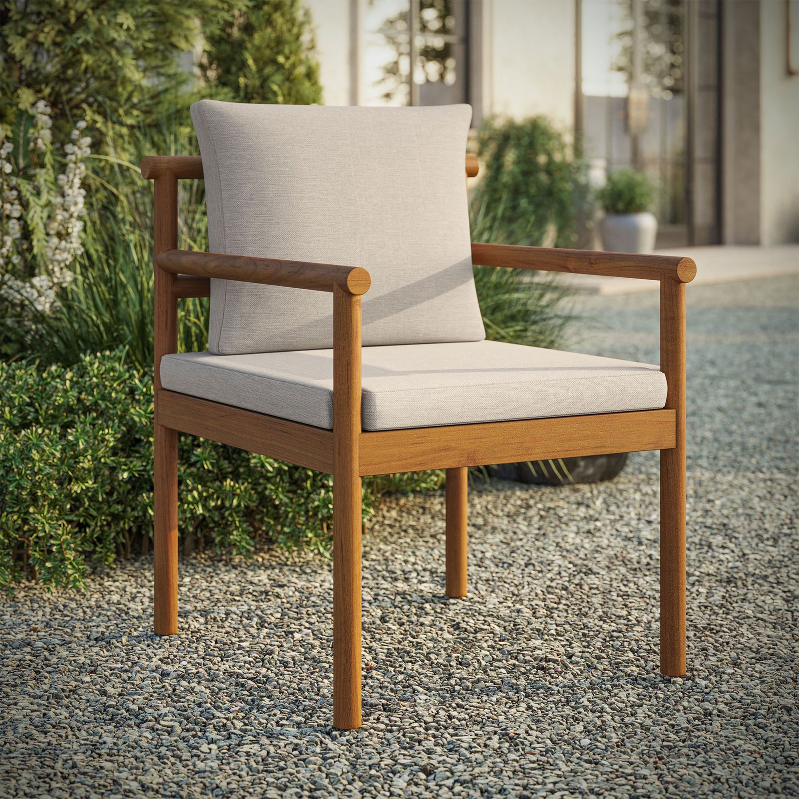 Teak outdoor dining chair with light cushions styled on gravel patio beside lush garden greenery. || EEI-7561-NAT-SAI || front_angle_room