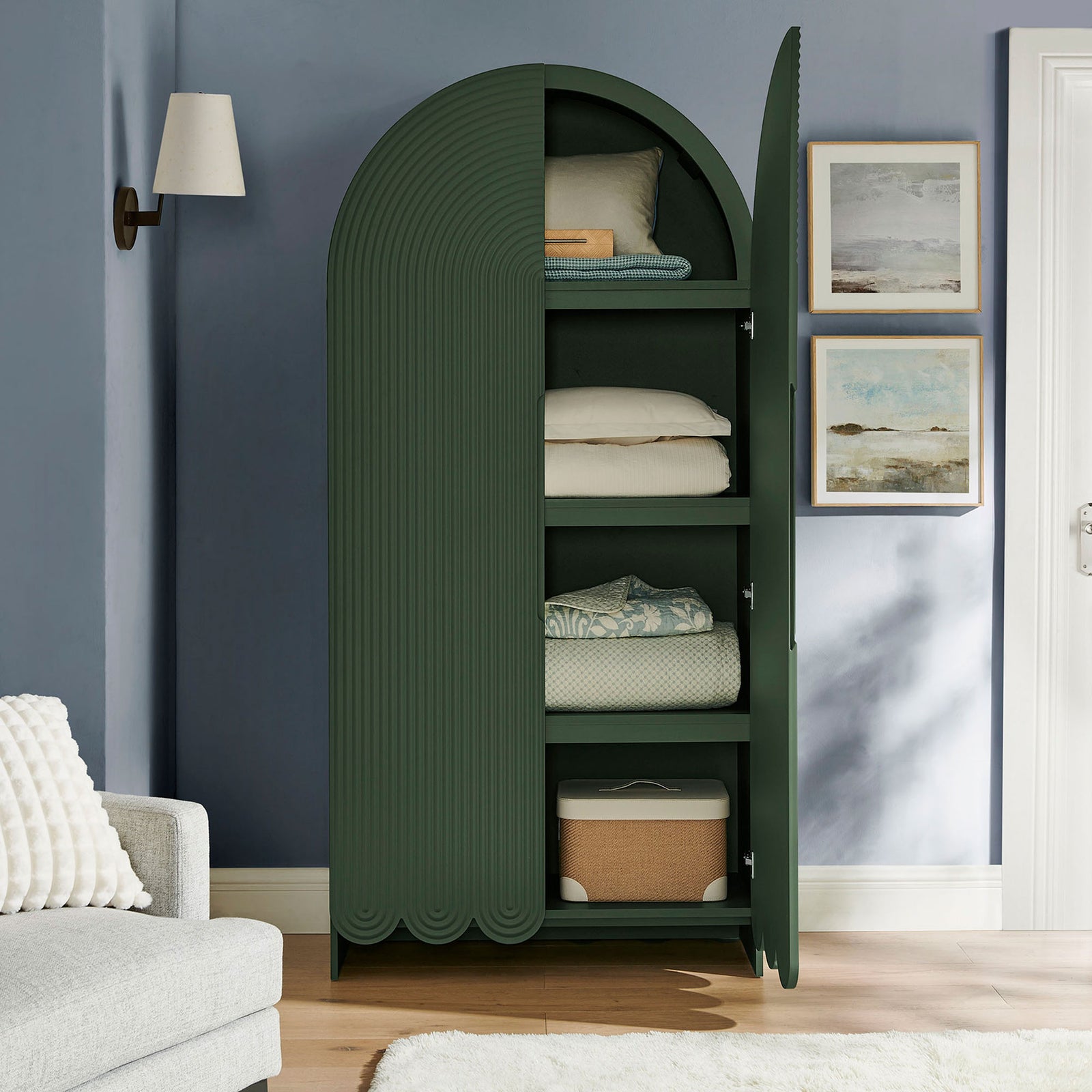 Hunter green arched cabinet with doors open, neatly storing folded bedding and baskets || EEI-7570-HGR || front_open_room