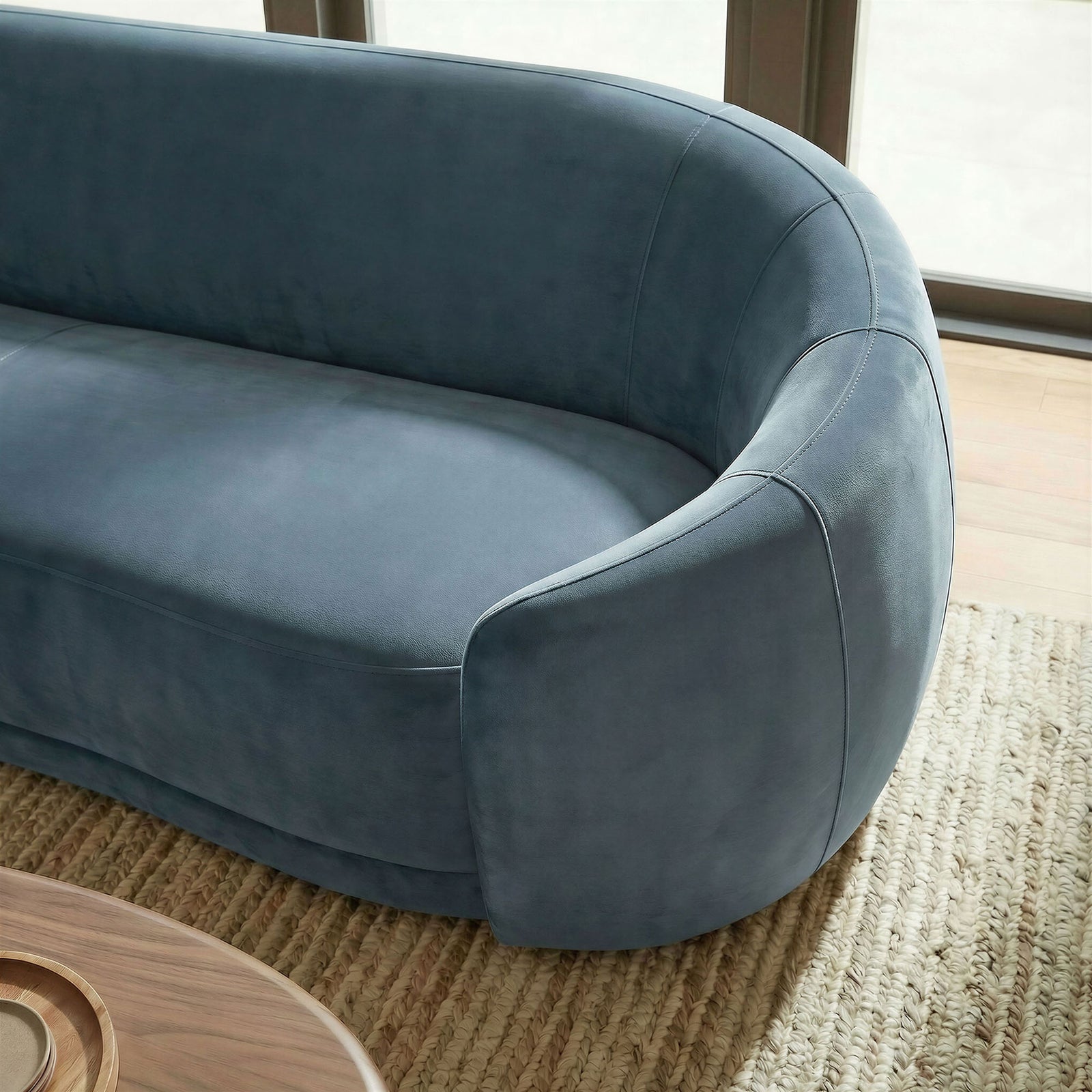 Close-up of the curved sofa corner in cadet blue velvet styled on a textured neutral rug. || EEI-7581-CAB || detail_room