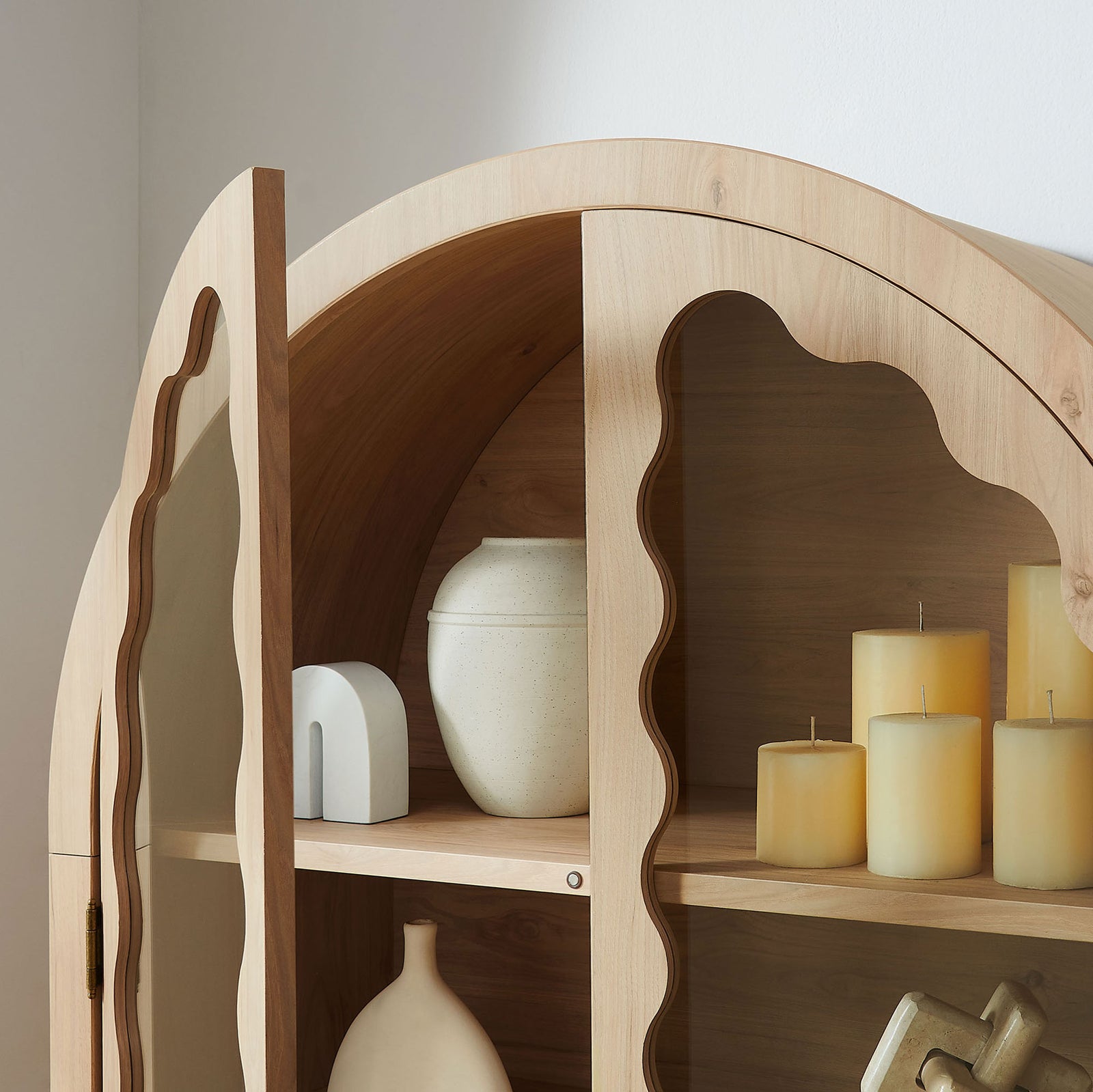Arched upper shelves of the light oak cabinet styled with candles and ceramics || EEI-7589-LOA || detail_room