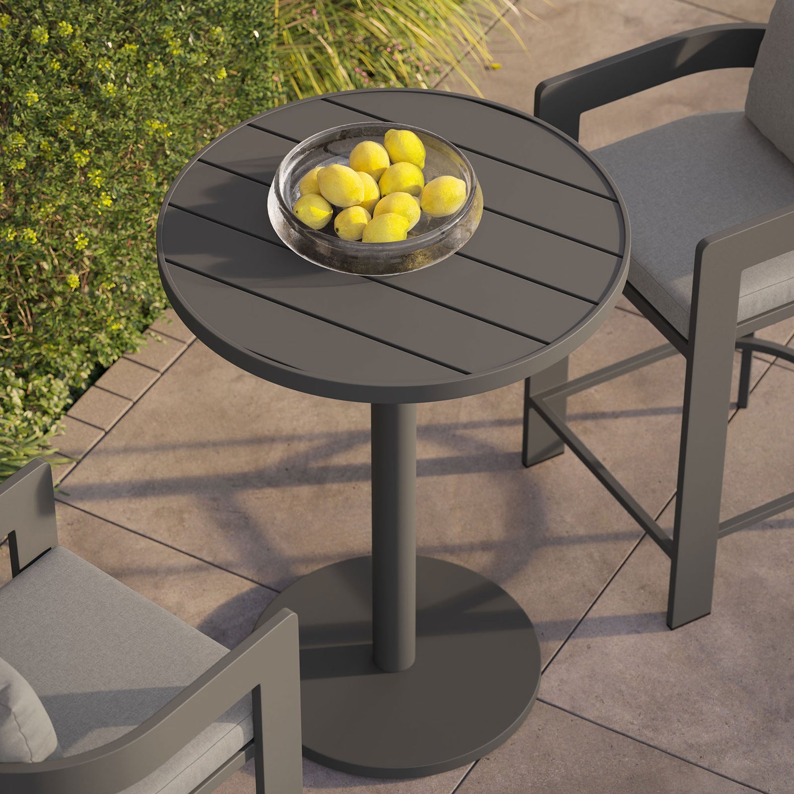 Lifestyle view of round gray bar table on patio topped with a bowl of lemons beside bar chairs || EEI-7594-GRY || top_angle_room