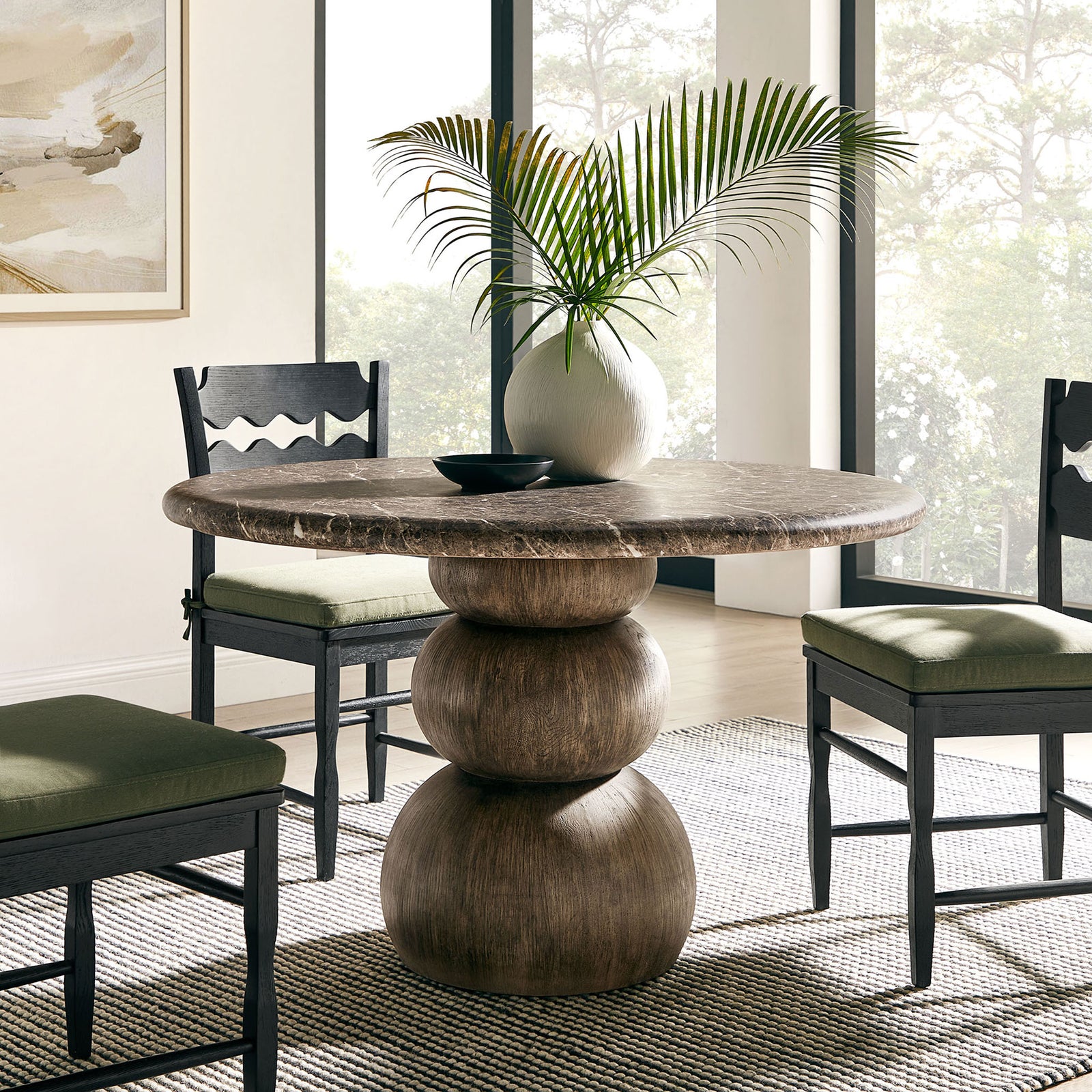 Round dining table centers a bright dining room, paired with upholstered chairs and greenery || EEI-7624-EMP || front_angle_room
