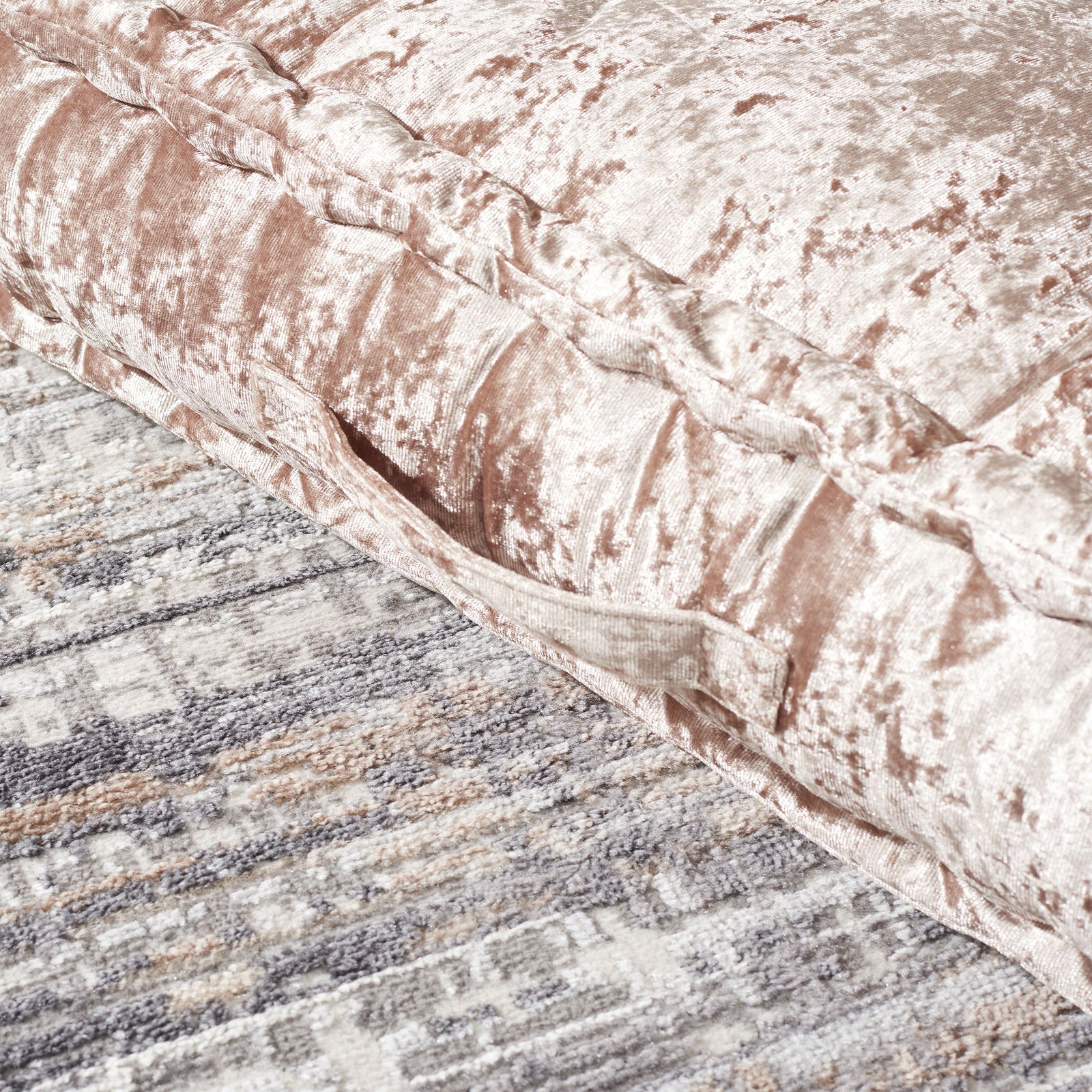 A stitched fabric handle lies along the champagne pillow's lustrous, padded side. || FLP1001F-1818 || handle_room