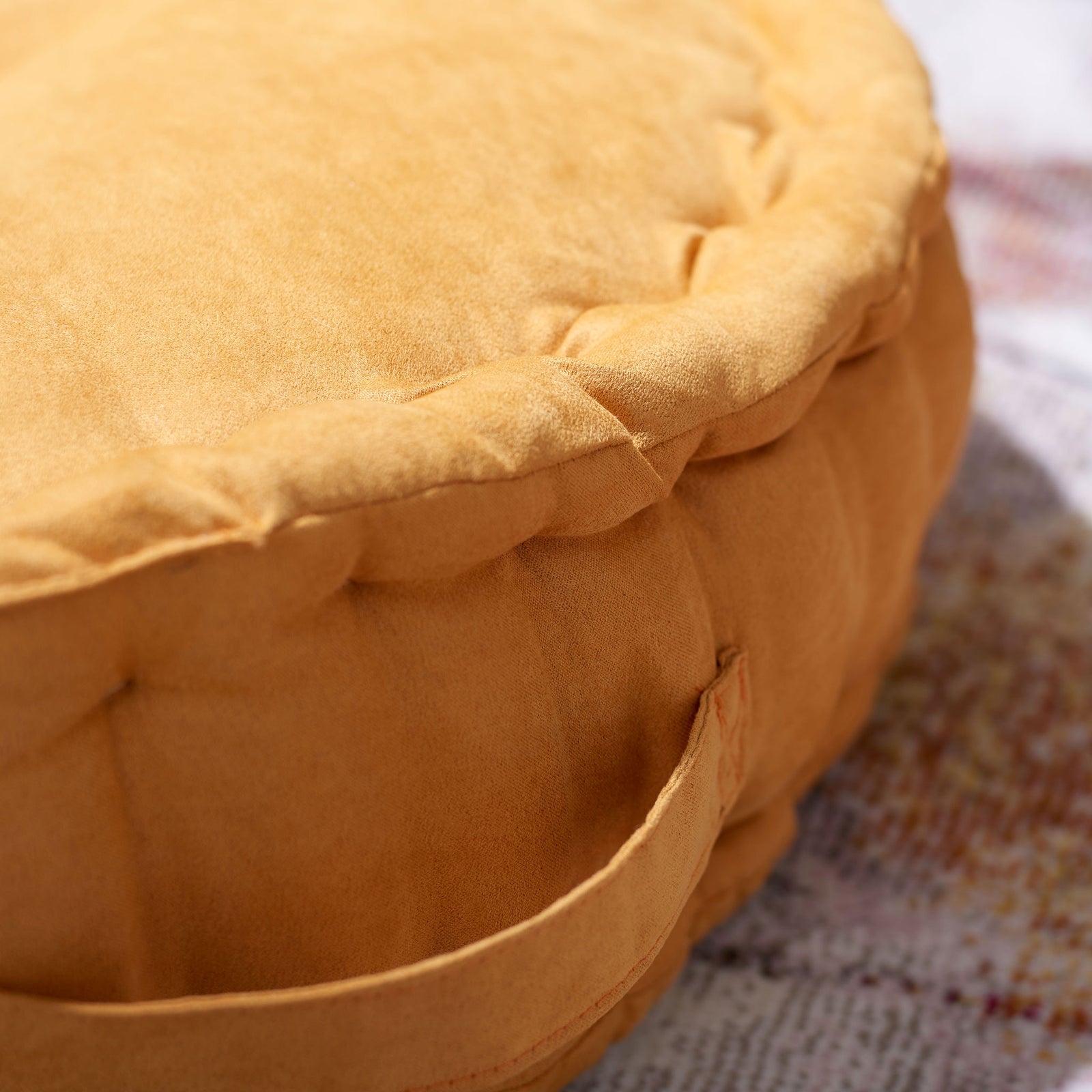 Soft mustard fabric and rounded, stitched folds frame the cushion's handy carrying loop || FLP1014A || detail_room