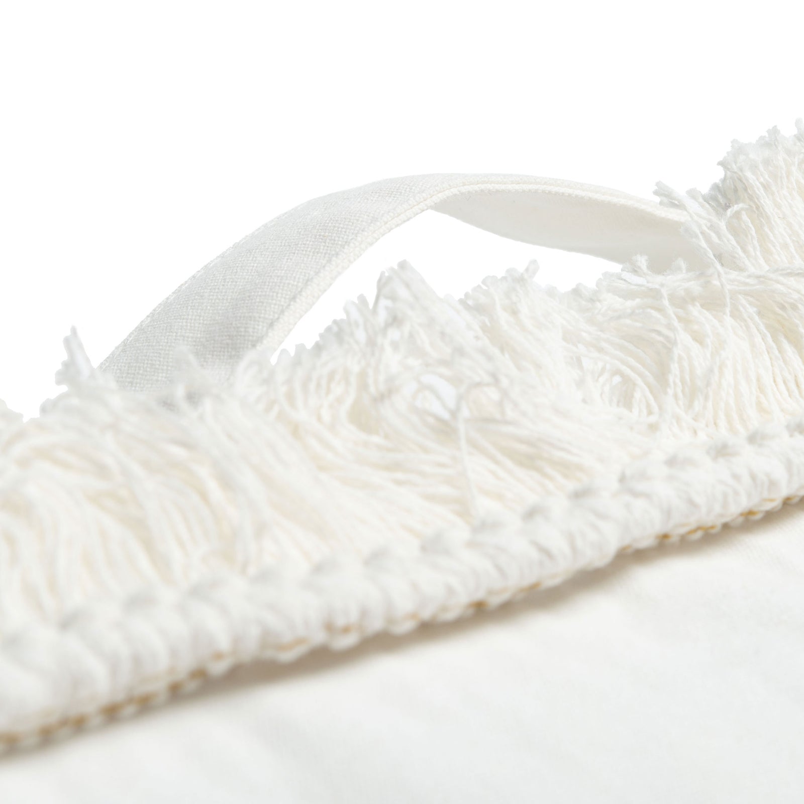 An ivory fabric carry loop rises above feathery fringe along the pillow's edge. || FLP1018A || handle_studio
