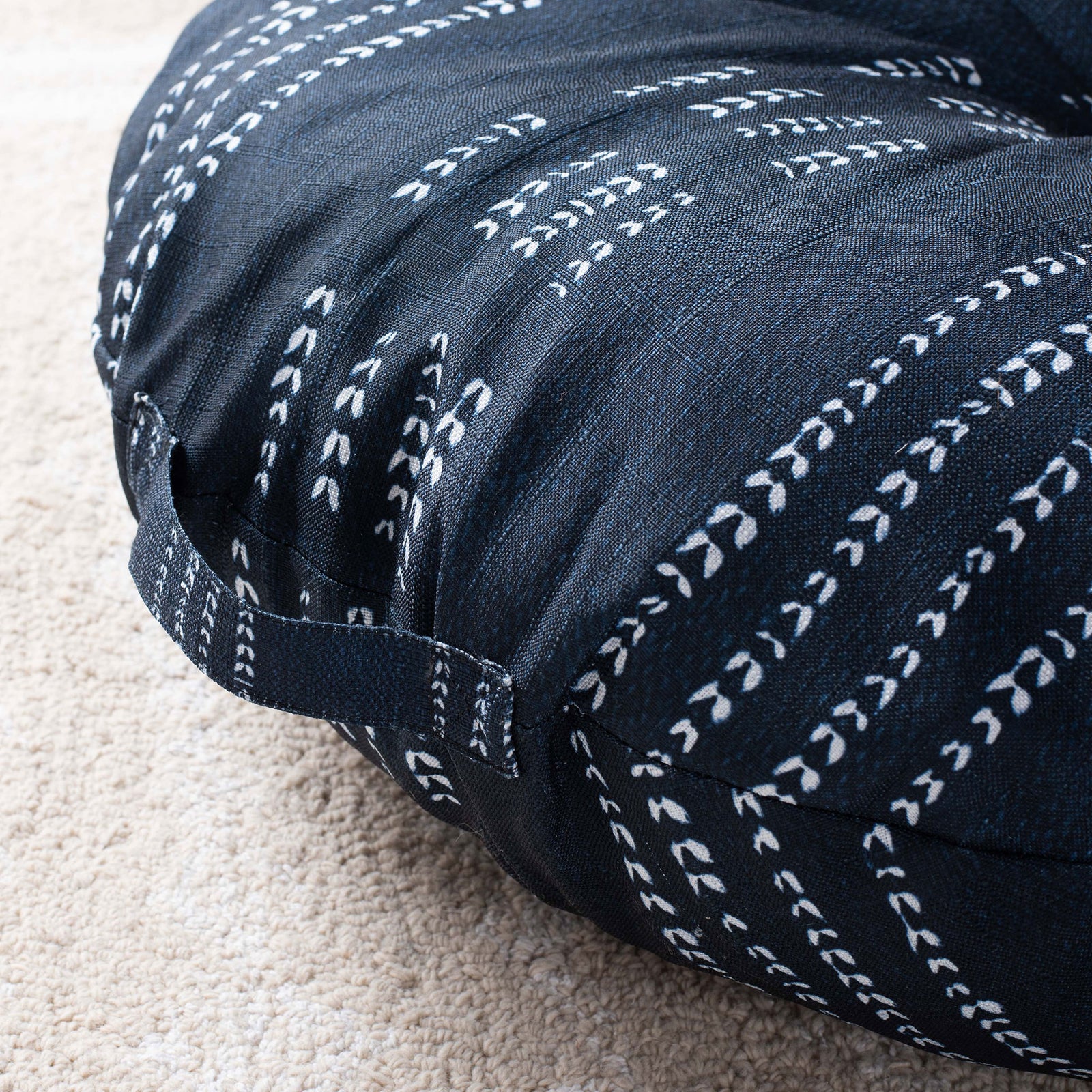A stitched carry loop rests against soft navy fabric detailed with ivory dashes. || FLP1023A-2626 || handle_room