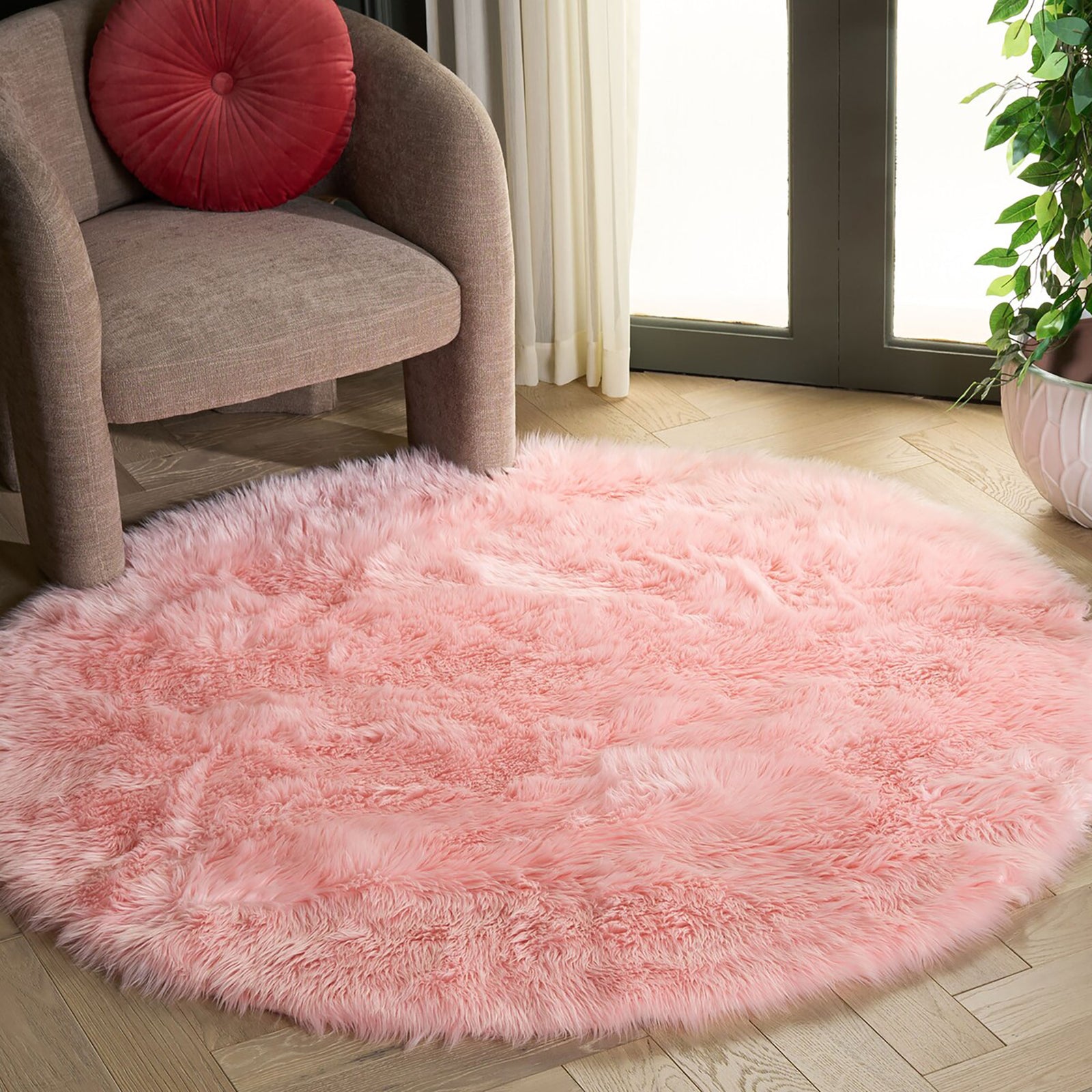 Round pink faux sheepskin rug with plush shag in a living room beside an upholstered chair || FSS235G-5R || top_angle_room