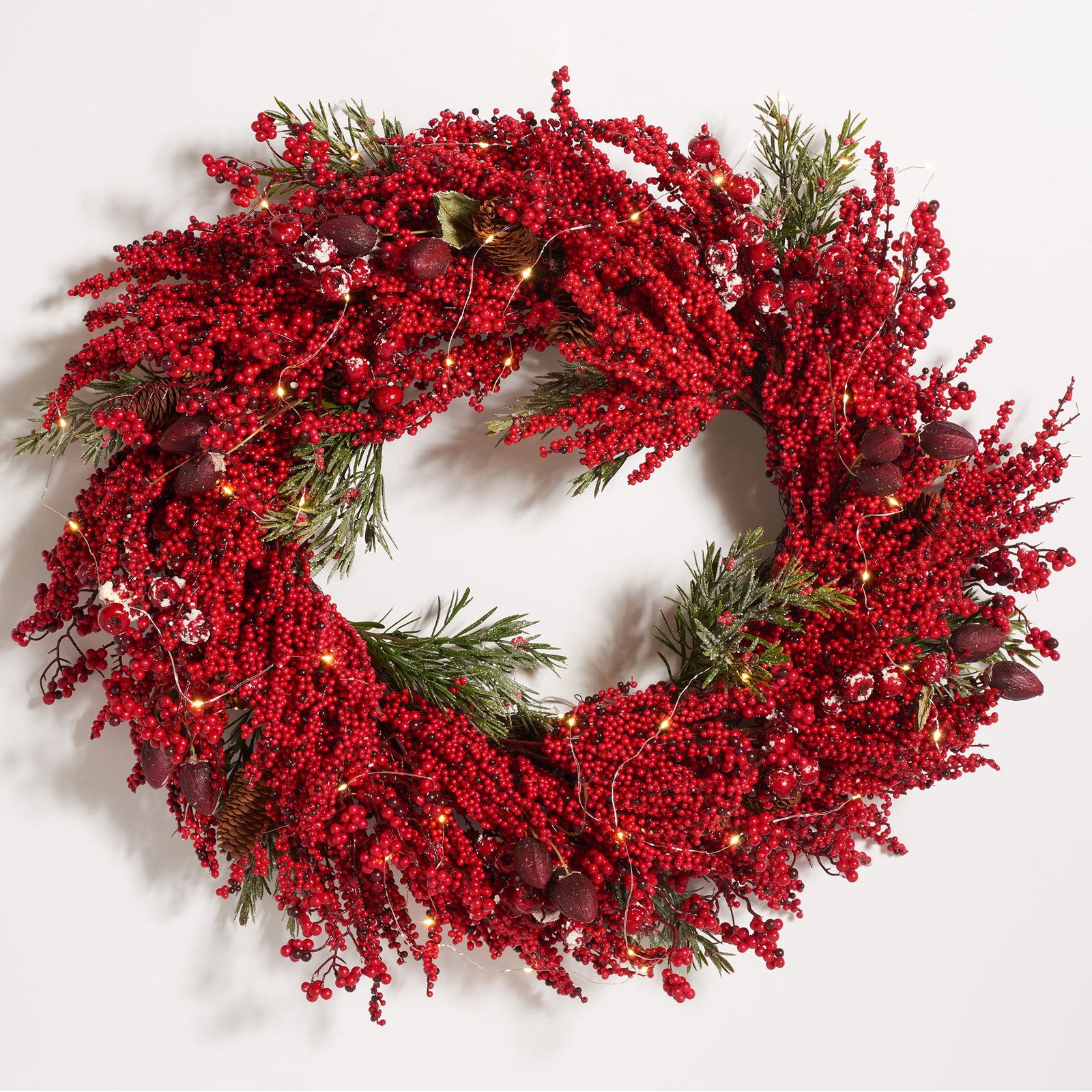 Warm LED lights twinkle among vivid red berries and pine branches. || FXP1093A || front_on_studio