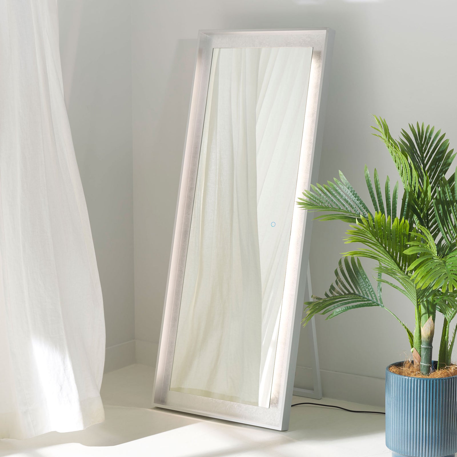 Soft LEDs brighten the silver leaf trim surrounding this freestanding full-length mirror. || LMR1015A || front_angle_on_room