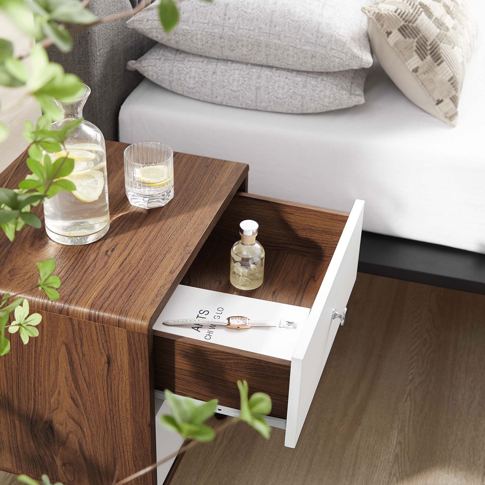 Nightstand styled beside a bed with drinks on top and an open drawer storing jewelry and bedside items. || MOD-7017-WAL-WHI || storage_open_room