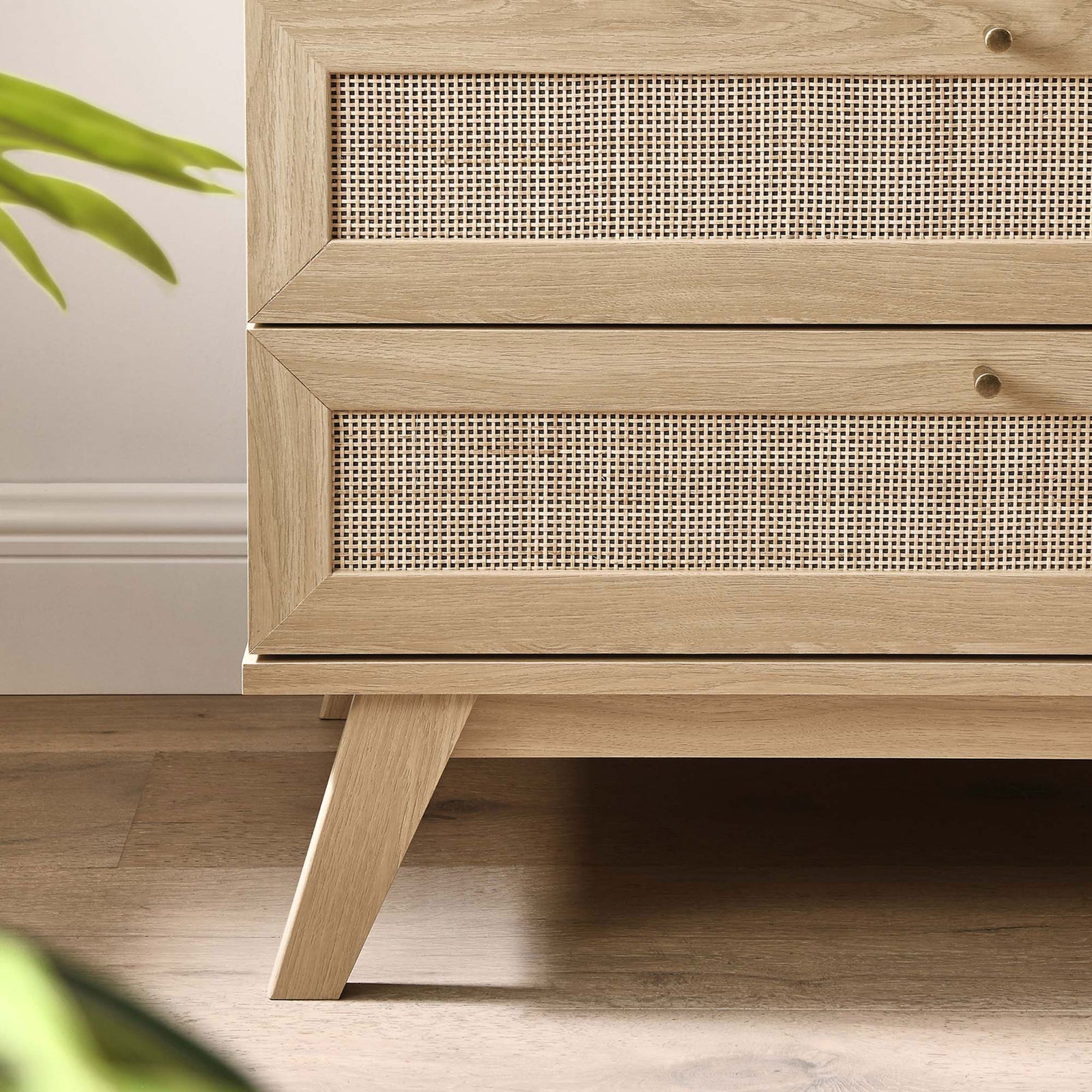 Lower corner of oak dresser showing angled leg and rattan drawer front over warm wood floor || MOD-7051-OAK || leg_room