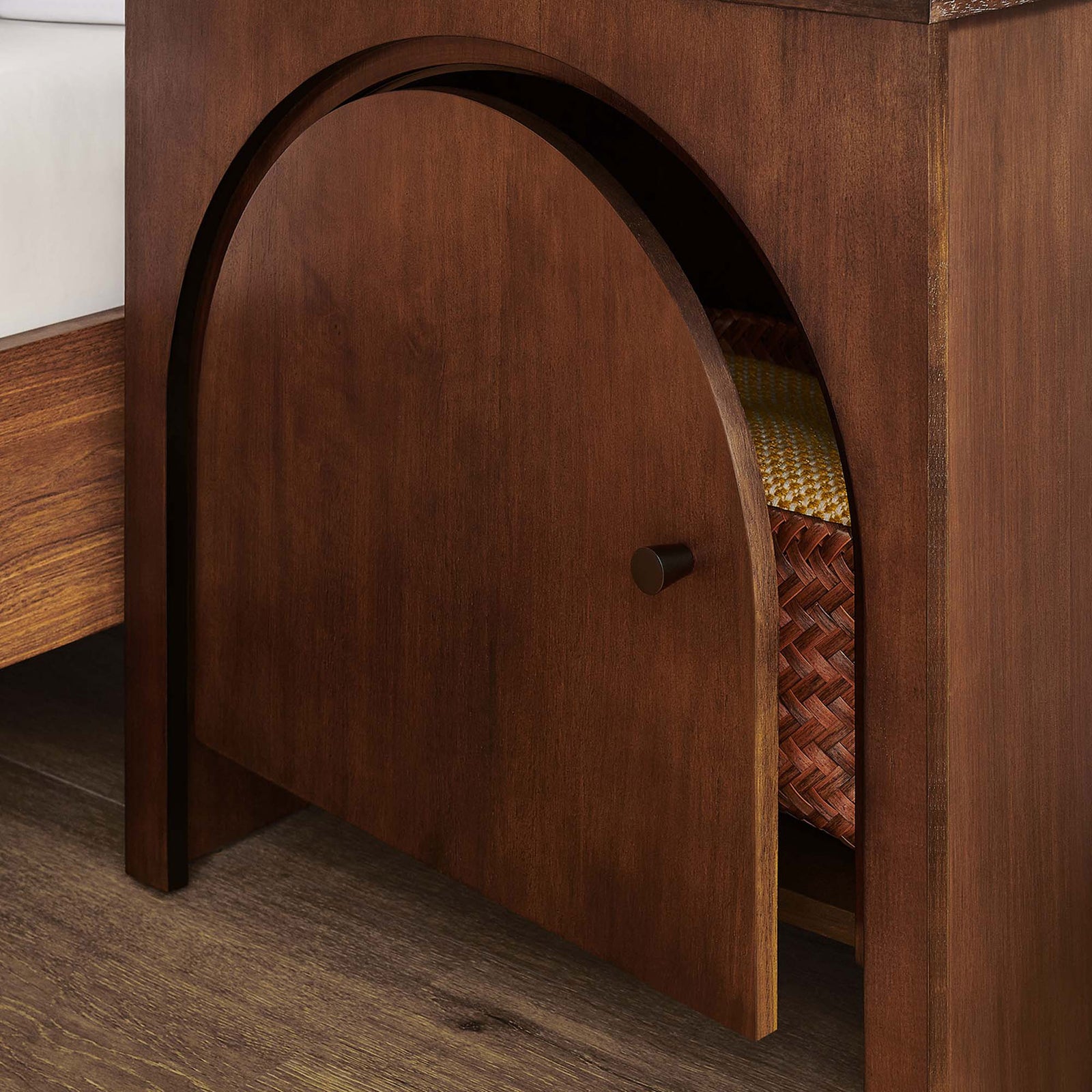 Appia arched door nightstand in walnut beside a bed, with cabinet partially open to access woven storage basket || MOD-7109-WAL || front_angle_open_room