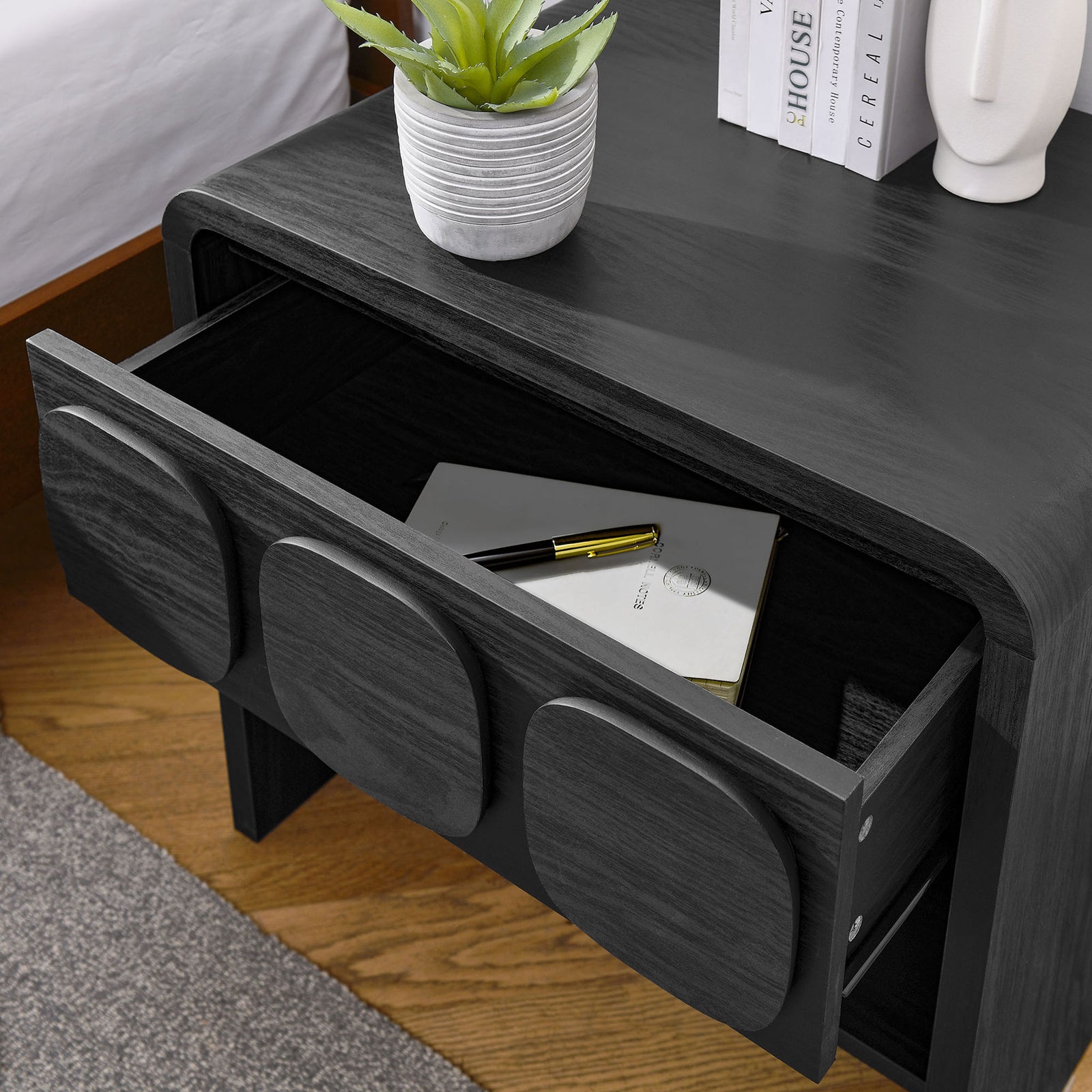 Black nightstand beside a bed with drawer open, showing storage for books, journals, and nighttime accessories. || MOD-7160-BLK || storage_open_room