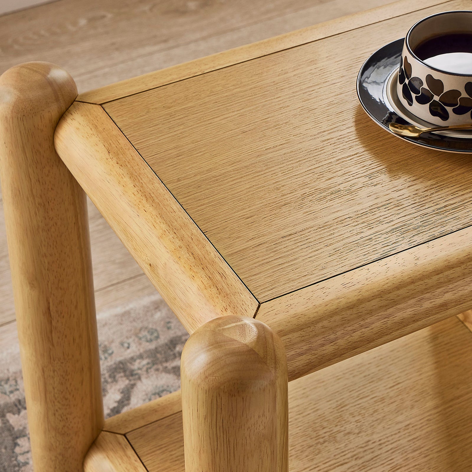 Arcus oak tabletop styled with a patterned cup and saucer, emphasizing the smooth wood grain finish. || MOD-7226-OAK || detail_room