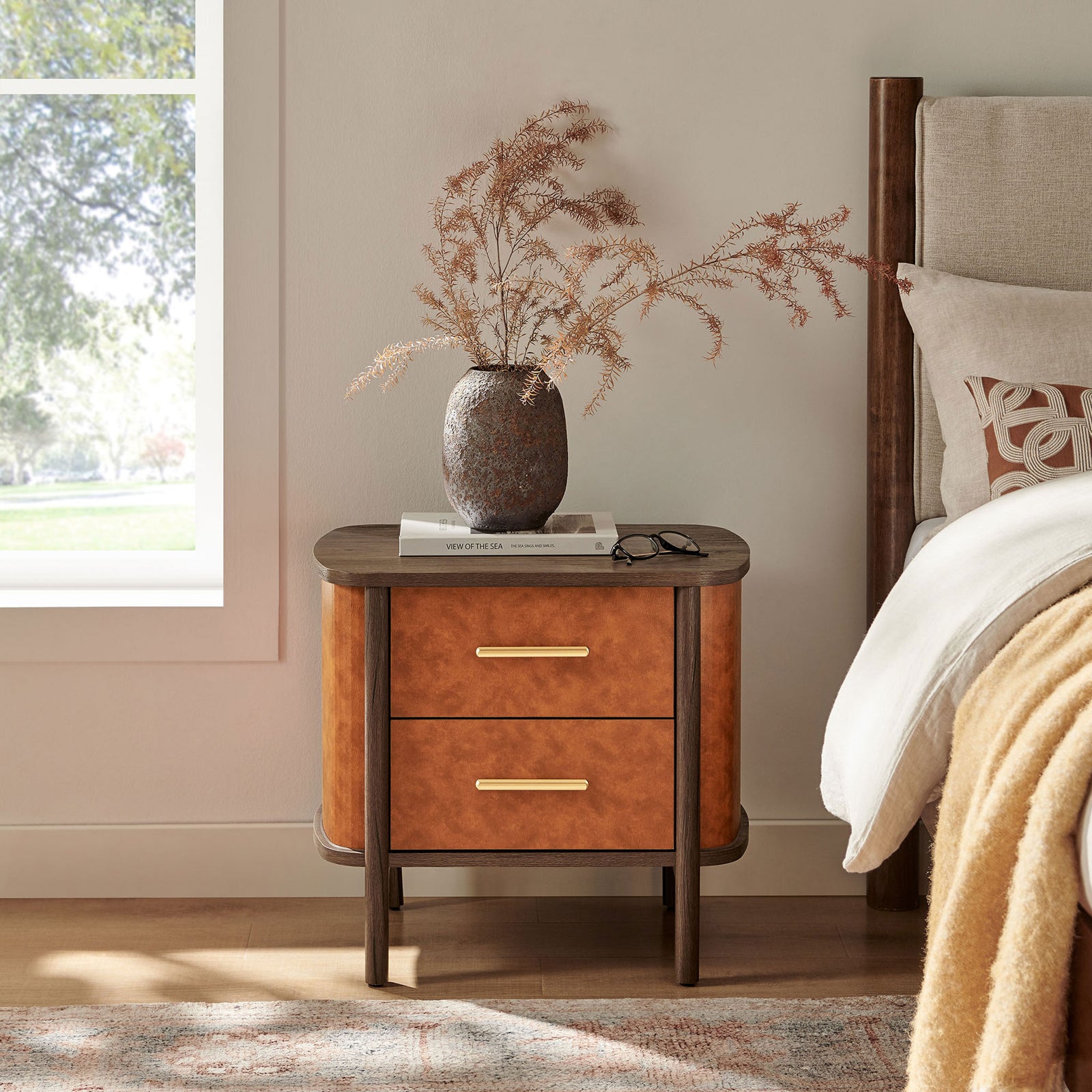 Curved vegan leather nightstand beside a bed, styled with decor for a cozy modern bedroom || MOD-7237-WAL-TAN || front_angle_room