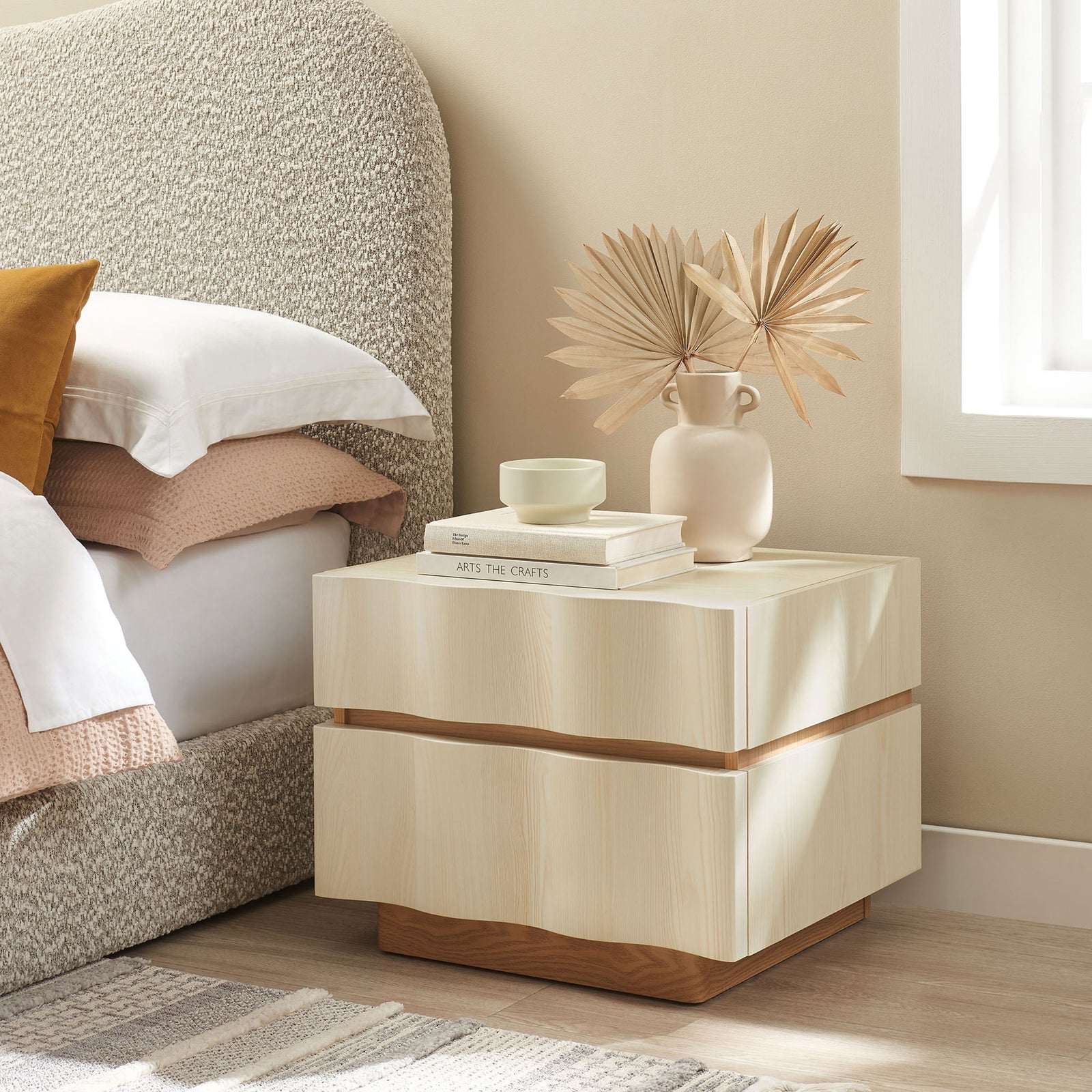 Isola nightstand next to a bed, styled with neutral decor to highlight its wave drawers and warm plinth base. || MOD-7243-WHI-LOA || front_angle_room