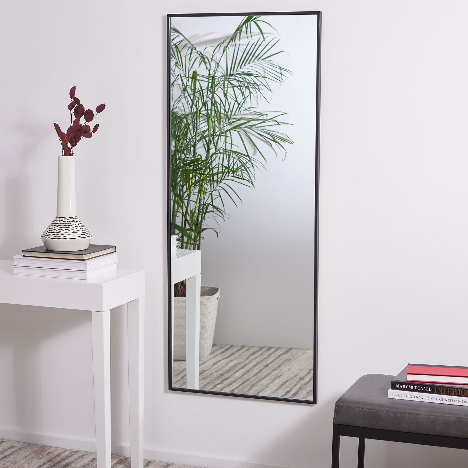 Tall black-framed mirror reflects greenery and adds depth to a bright room || MRR1062A || front_room