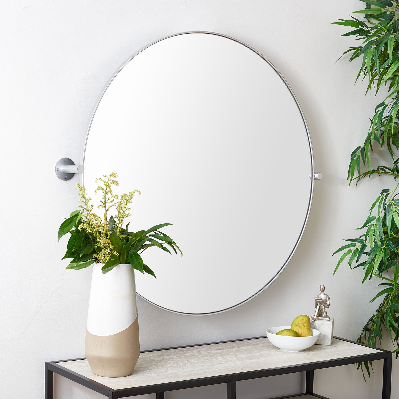 A silver-framed round mirror with exposed side mounts brings a light, modern touch above a console || MRR2000C || front_room