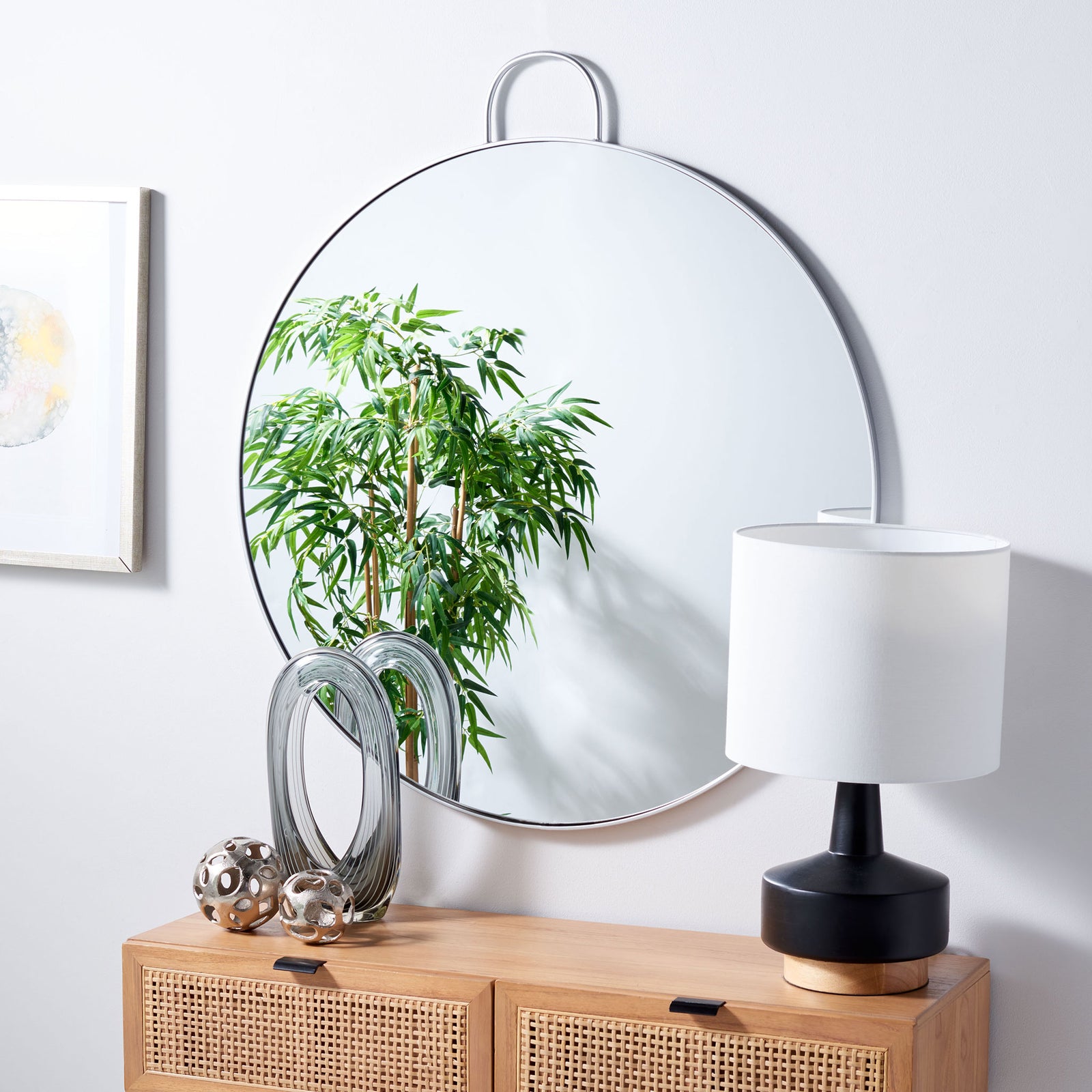 A silver-framed round mirror adds a soft gleam above a light wood console || MRR2002B || front_angle_room