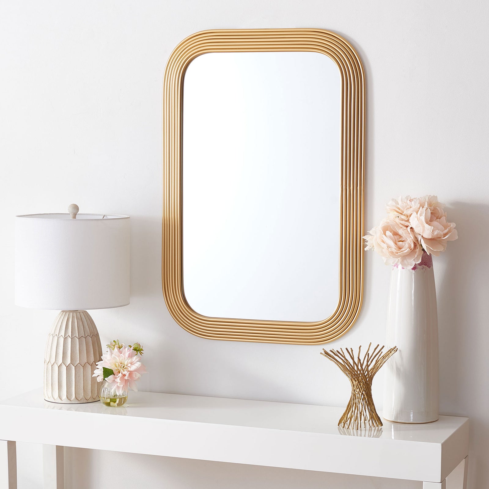 Brass-toned ribbed mirror adds warmth above a white console table || MRR2003C || front_room