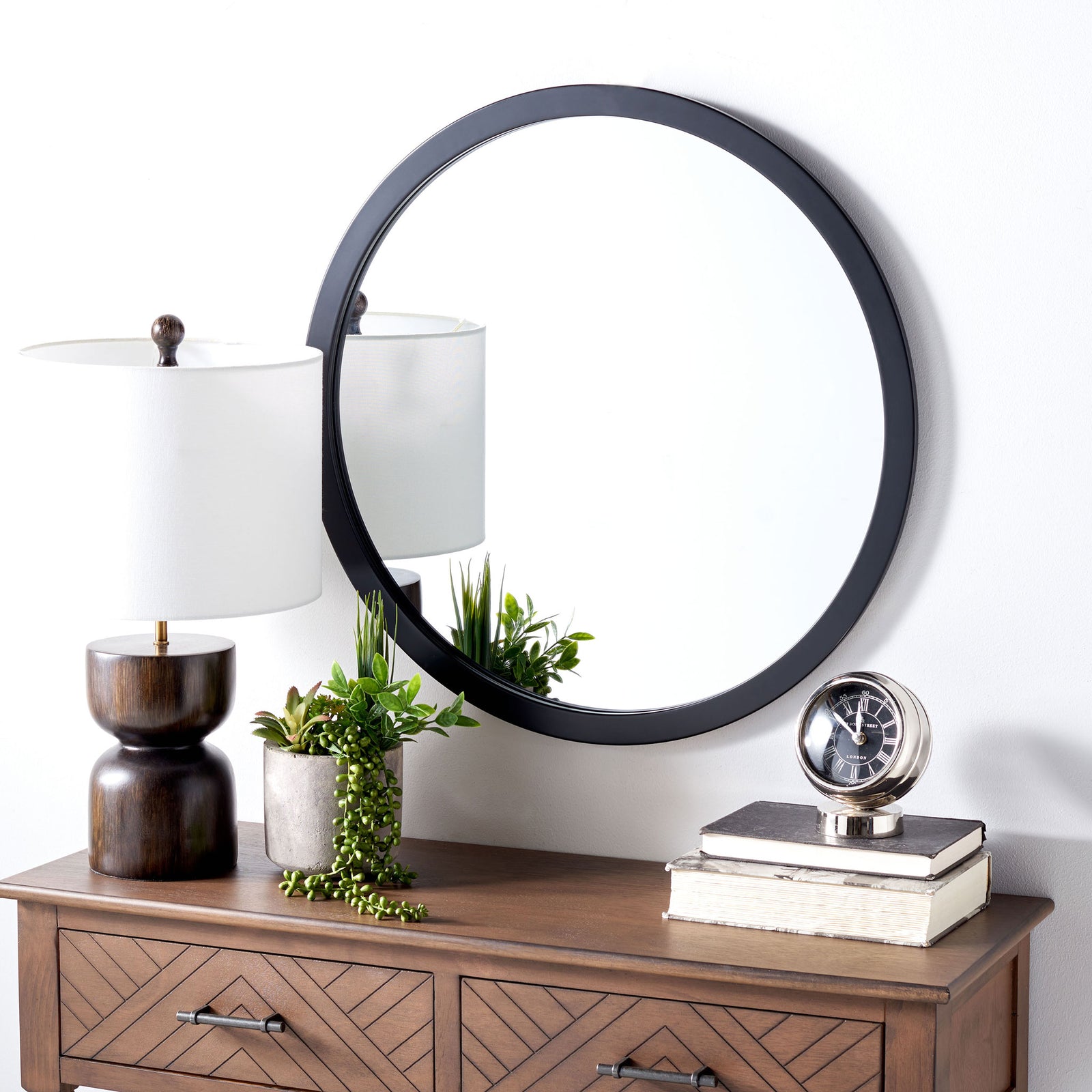 A round black-framed mirror adds crisp contrast and dimension above a wood console || MRR2006C || front_angle_room