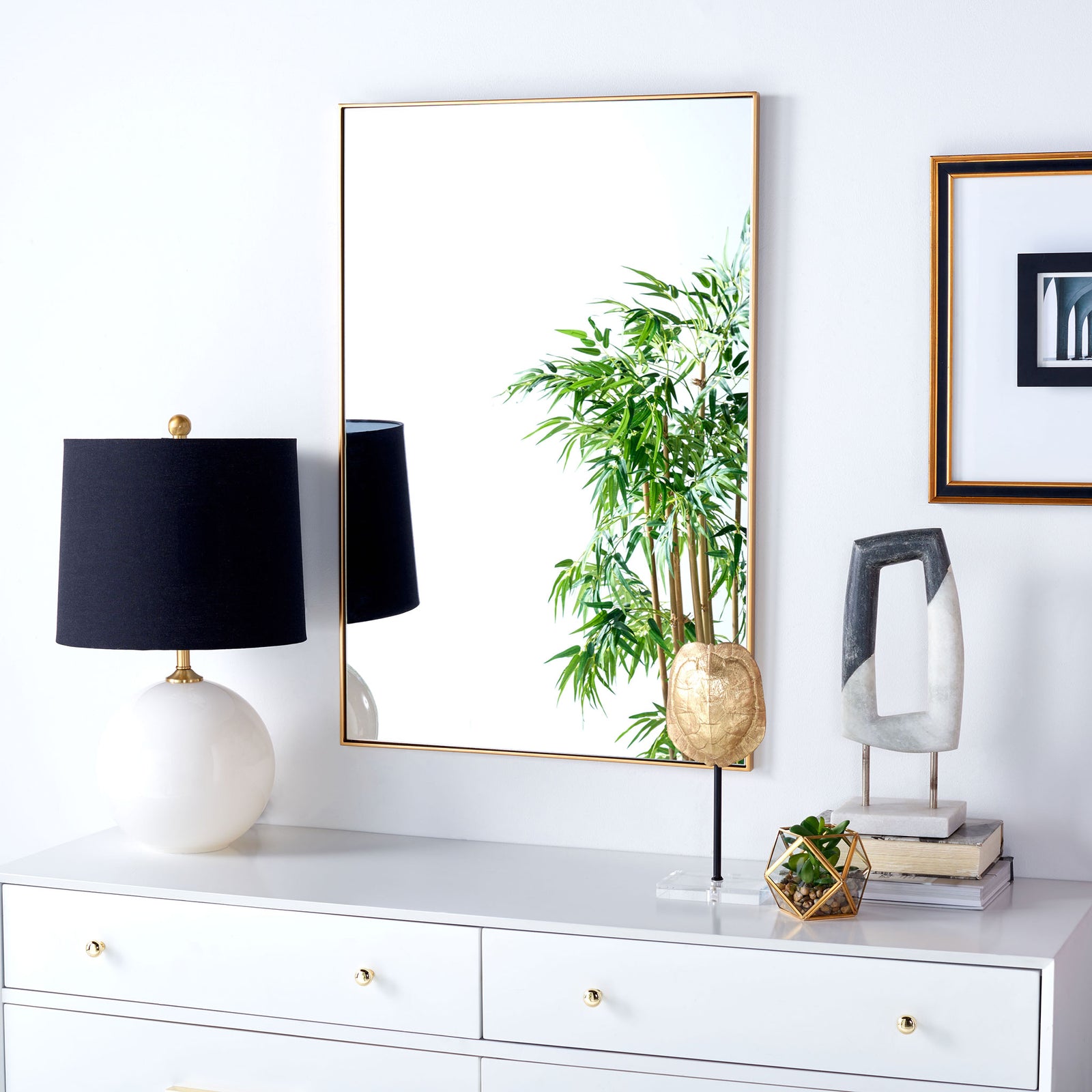 A wall-mounted brass-framed mirror adds warmth and light above a white dresser. || MRR2011C || front_room
