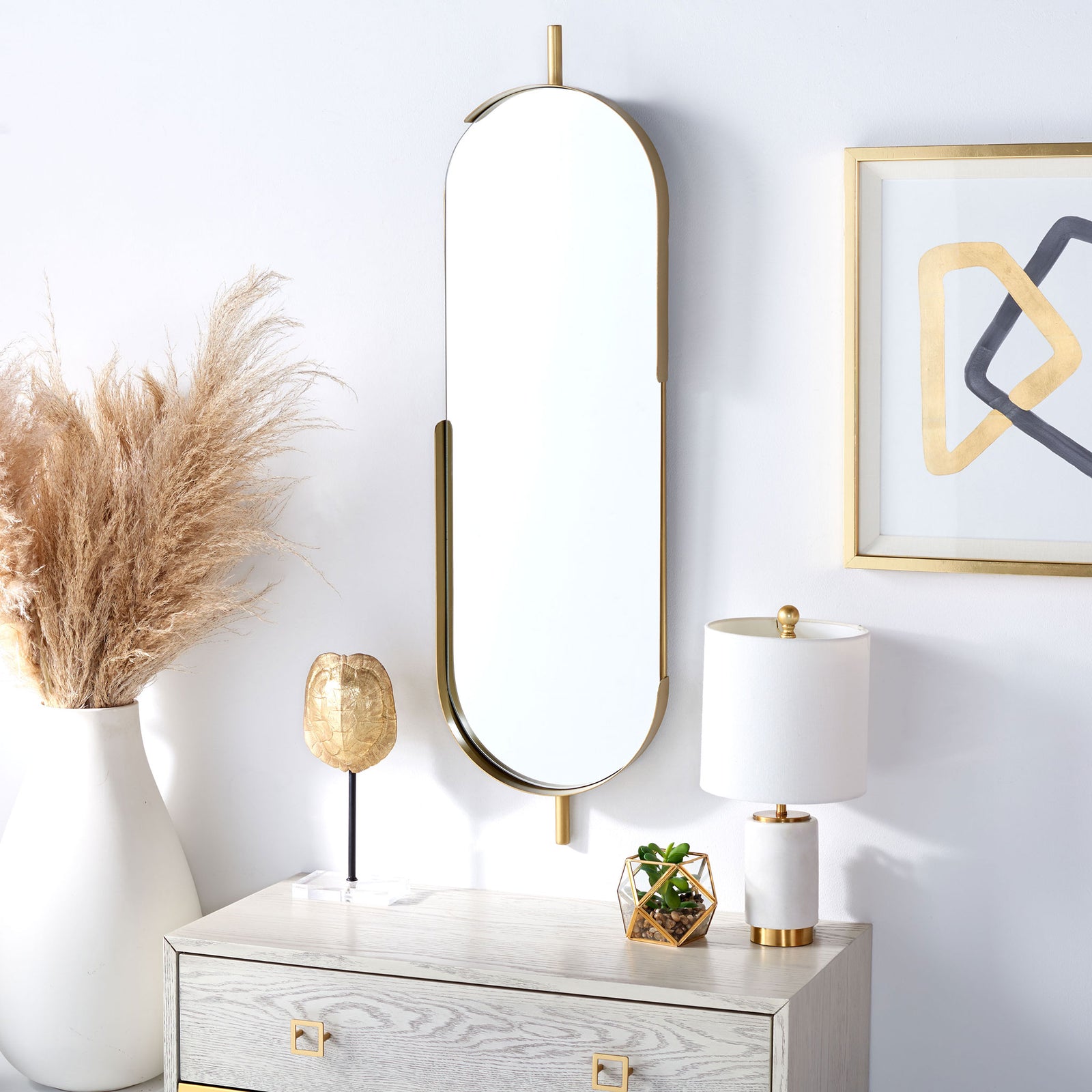 A tall brass-toned mirror adds a sculptural accent above a pale wood cabinet. || MRR3051A || front_angle_room